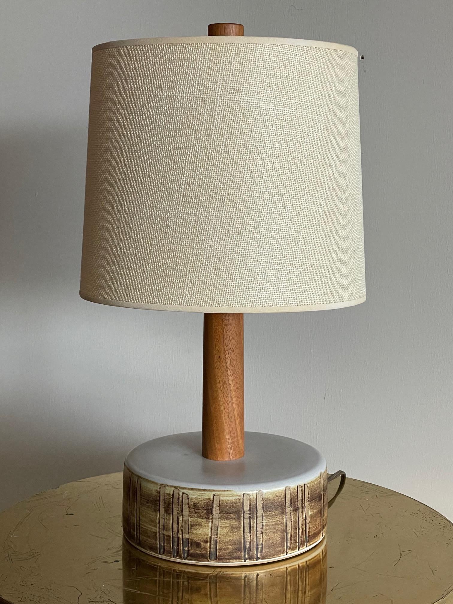 An unusual lamp by Marshall Studios/Martz. Decorated base with long walnut stem. Includes original shade/finial.
