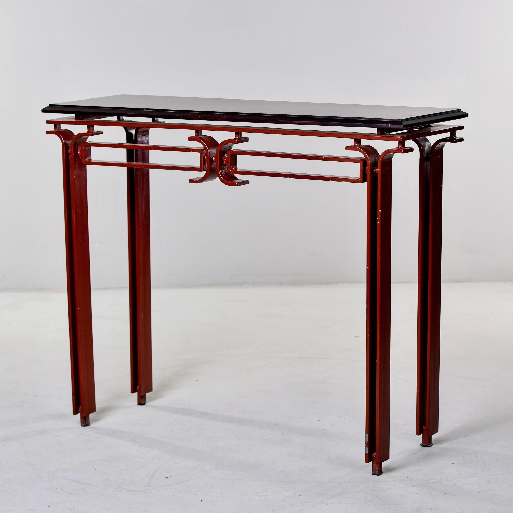 Found in Italy, this vintage circa 1980 console table has an unusual and sculptural metal base with an oxblood painted finish and veneered wood top. Veneer appears to be rosewood, but we cannot be certain. Unknown maker.