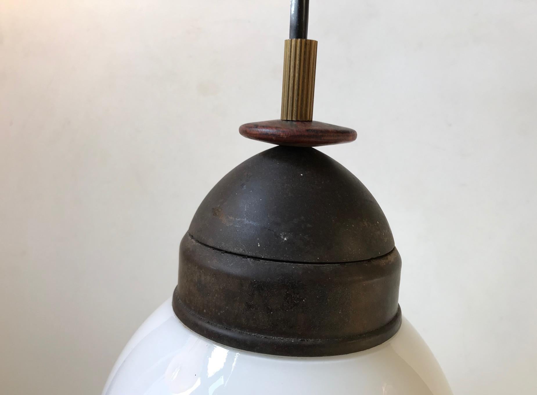 Curious and unique entrance hall or corridor pendant light composed of bakelite, brass, opaline glass and rosewood. Anonymous Danish maker circa 1950.