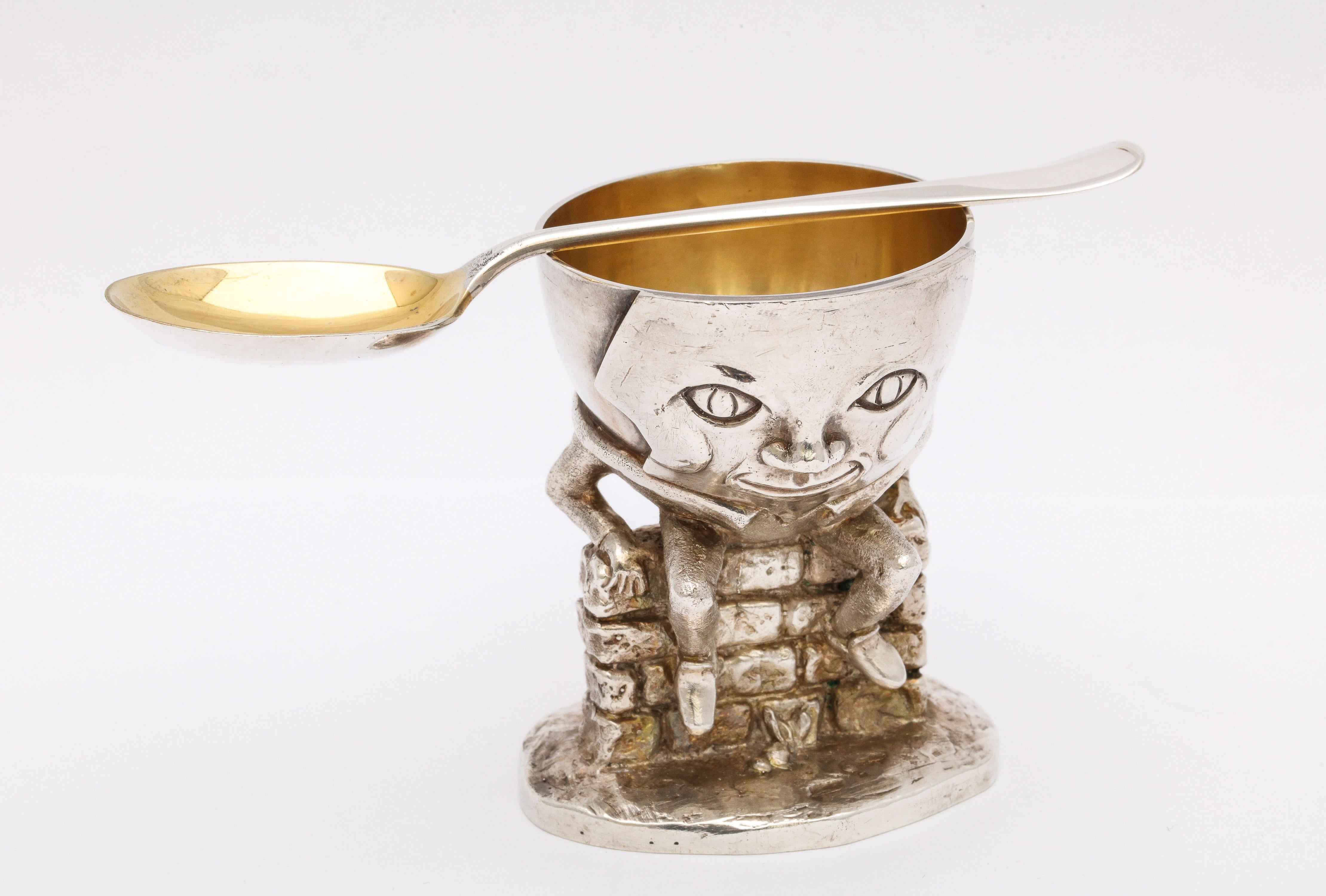 Unusual, midcentury, sterling silver, parcel gilt, humpty dumpty-form egg cup with matching spoon, London, year hallmarked for 1982, Atkin Bros. - makers. Inside of egg cup is gilded as is bowl of spoon. Egg cup stands 2 3/4 inches high x 2 1/4