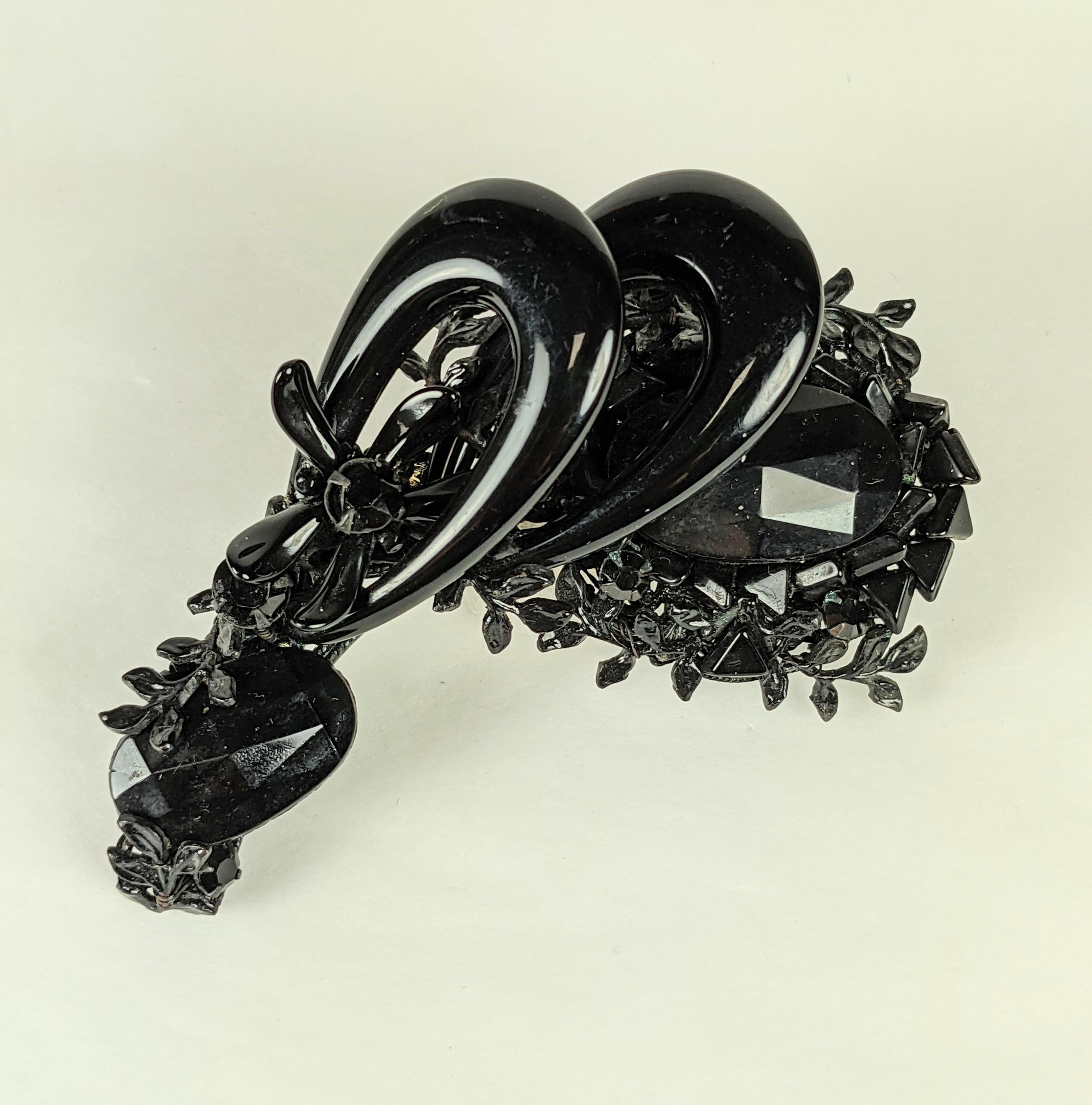 Stunning and dimensional Miriam Haskell Jet Loop Brooch from the 1950's. Elaborate jet stones of different cuts are embroidered onto a black filigree base A small jet flower is sewn growing out of a black glass loop.
Completely hand made. Signed.