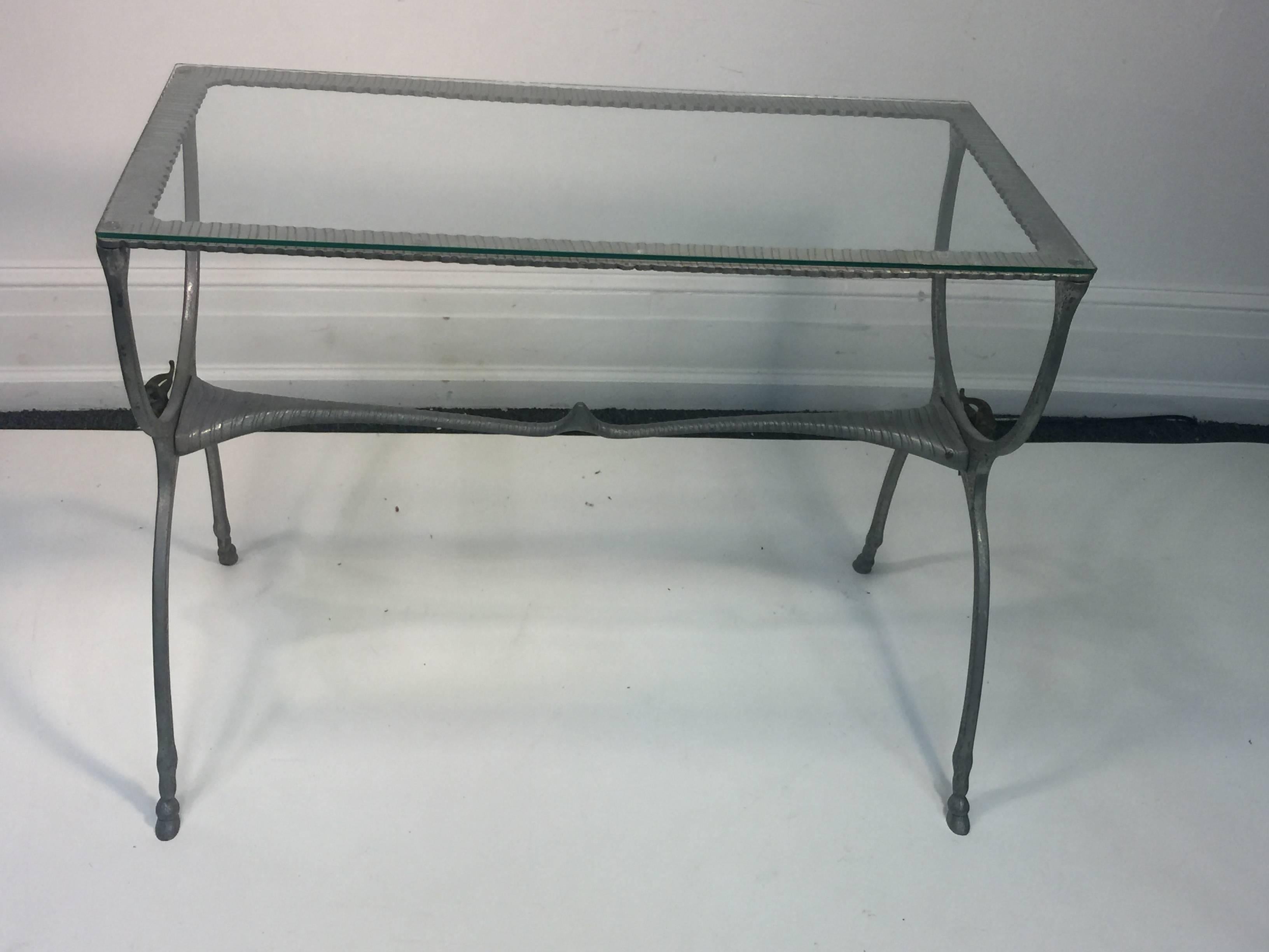 Interesting aluminum console table with hoof feet and bronze horned goat heads on either side of the base. Center connecting piece in the shape of a animal horn. Attributed to the Avant Garde aluminum sculptor Donald Drumm in the 1960s-1970s. Glass