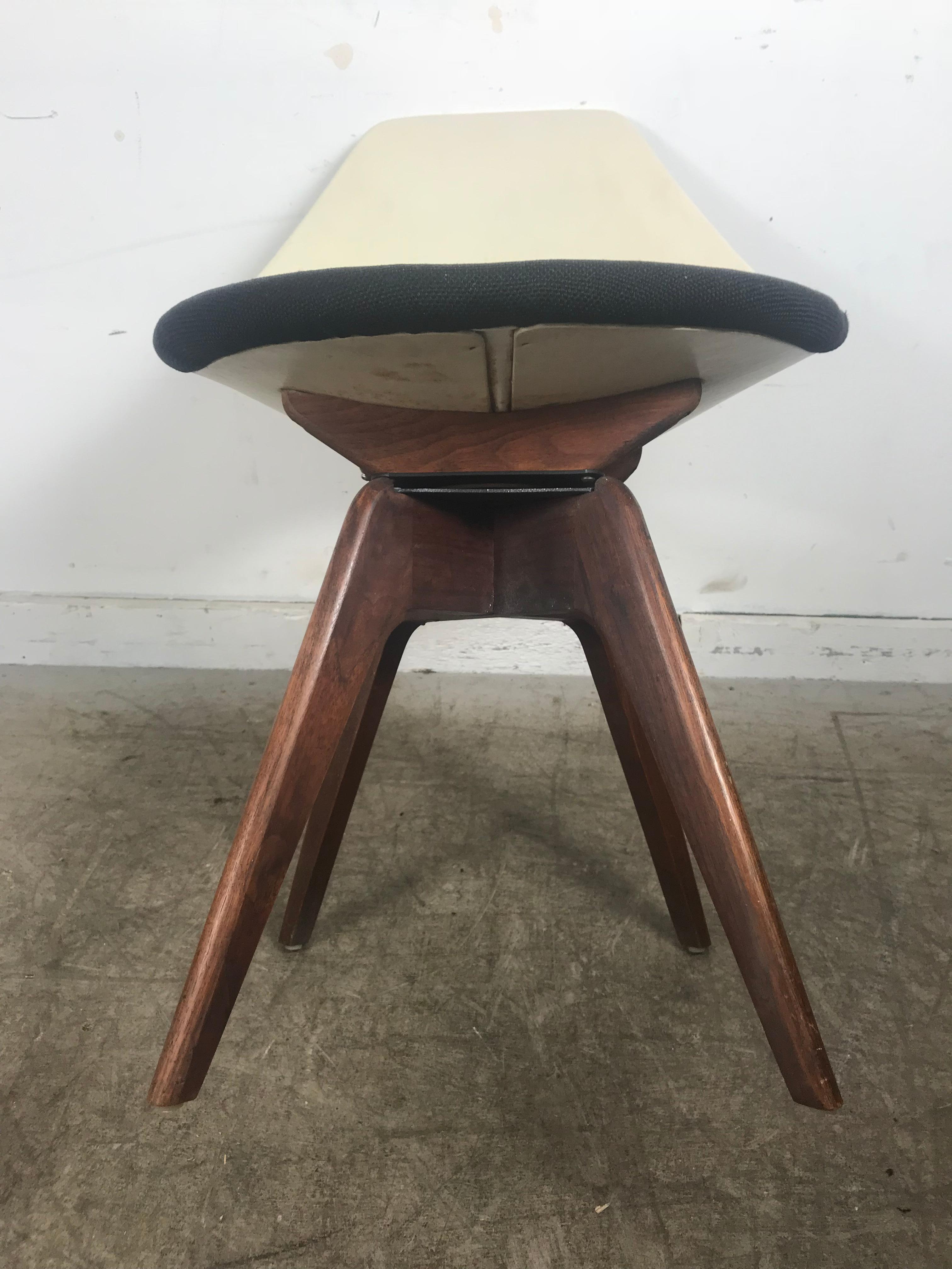 Adrian Pearsall meets Eero Saarinen, most unusual Mid-Century Modern swivel chair. Beautiful sculpted walnut base, moulded top, half black 1950s fabric, back white Naugahyde. All original condition, age appropriate wear, minor wear to black fabric.