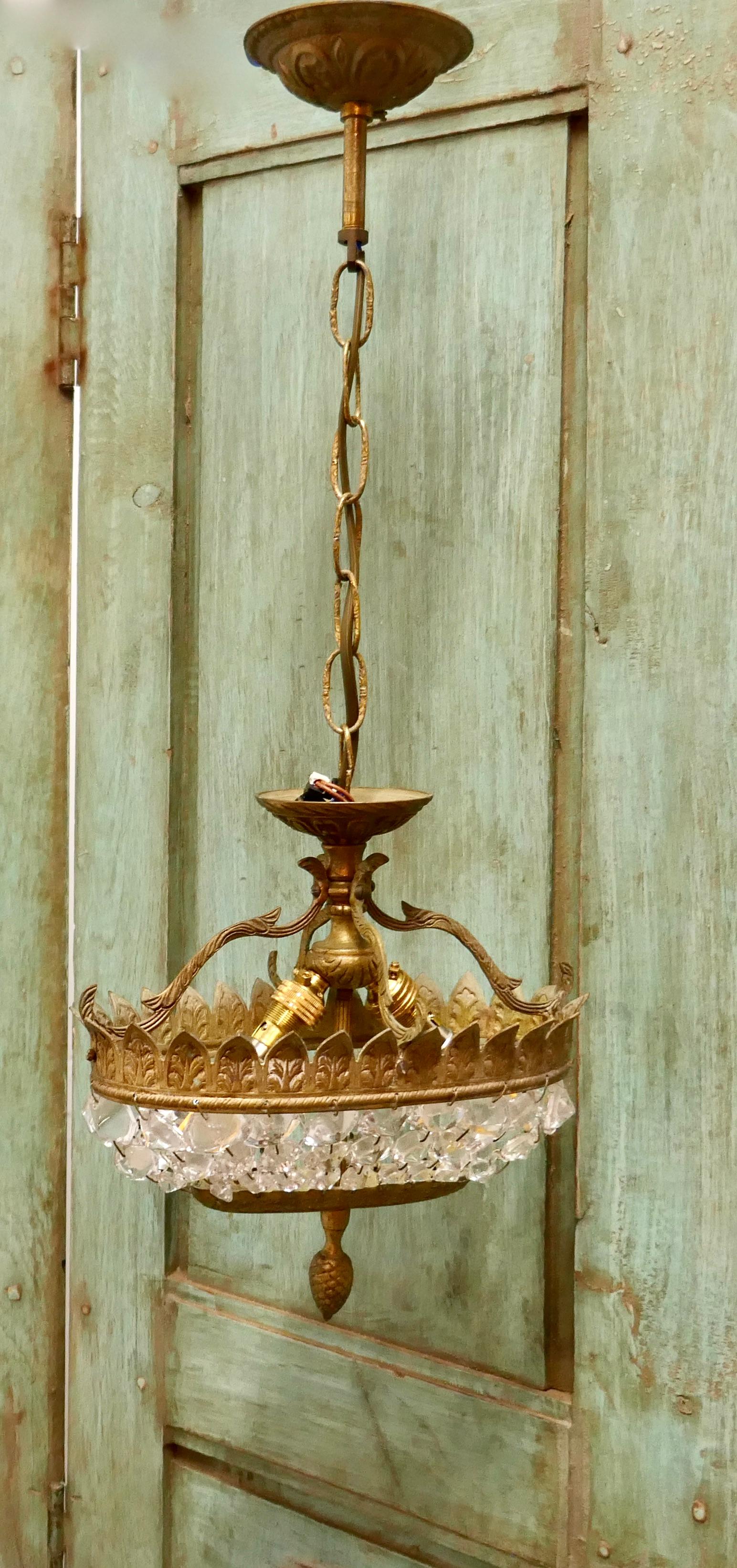 Unusual oval shaped French Empire style basket chandelier

This piece is an unusual oval shape, it has a decorative aged brass frame hung with chains of cut large crystal beads gathering in an oval at the base, it has a brass ceiling rose 
The
