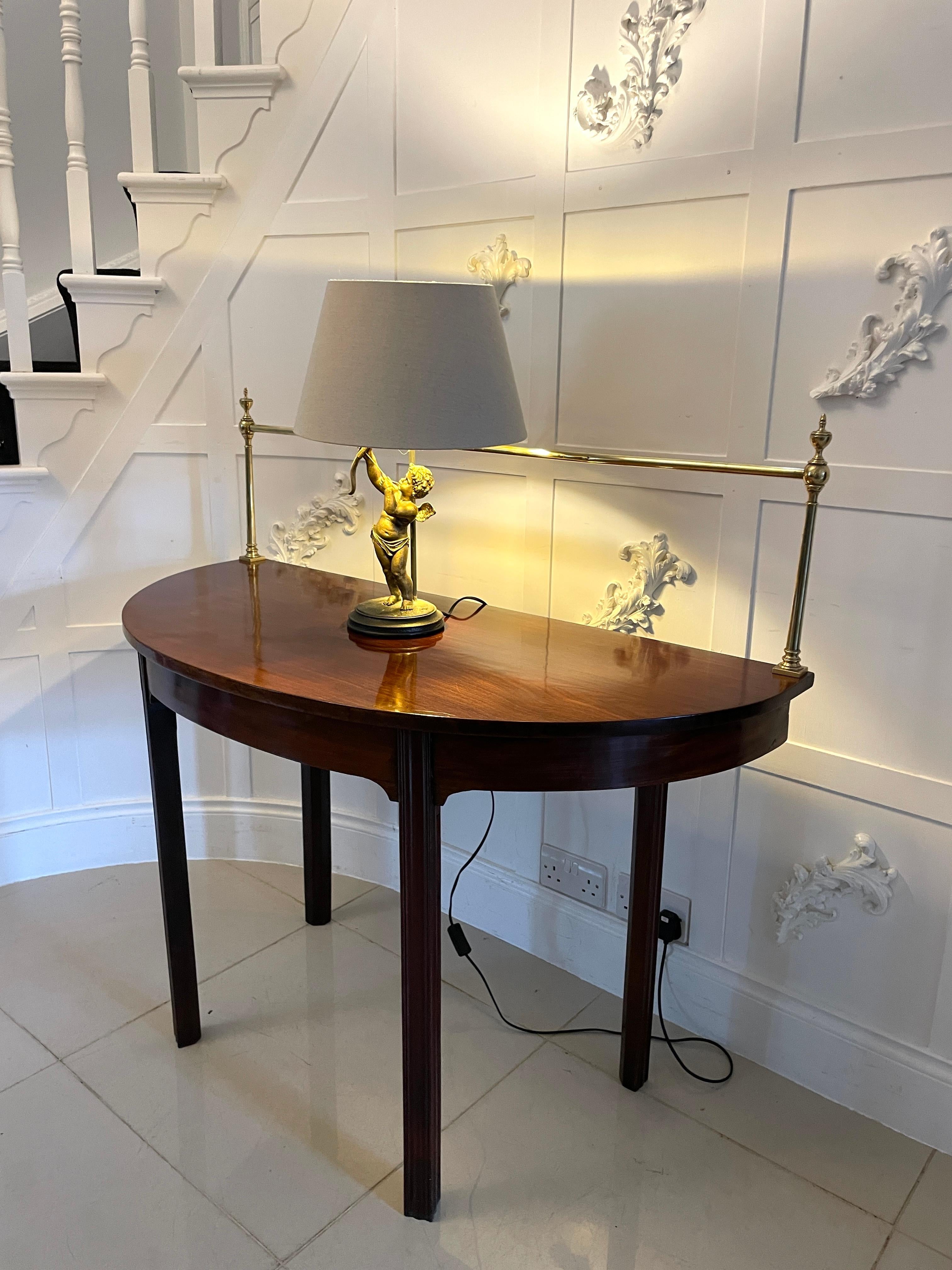Unusual Pair of antique George III quality mahogany demi-lune consoles tables having the original brass rails above a quality figured mahogany demi-lune shaped top, mahogany frieze standing on elegant square moulded chamfered legs 

An elegant pair