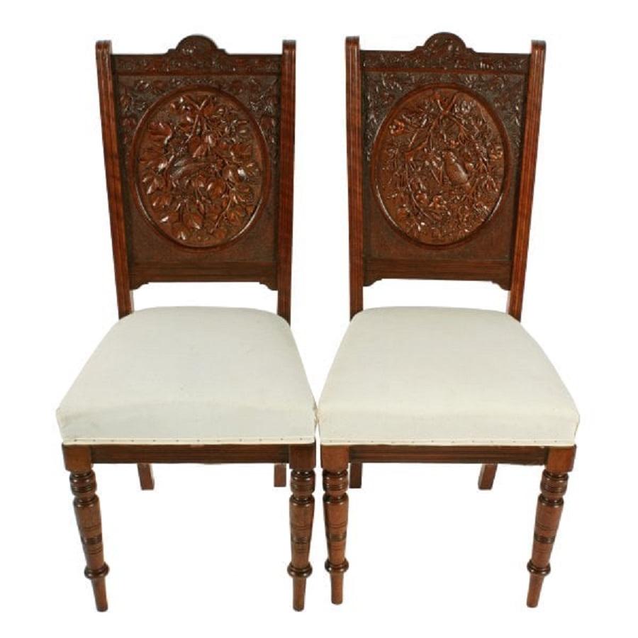 An unusual pair of late 19th century Victorian walnut chairs.

The chairs each have different oval carved panels backs of tropical birds, foliage and flowers and carved top rails.

The chairs are British in design but could have been made in