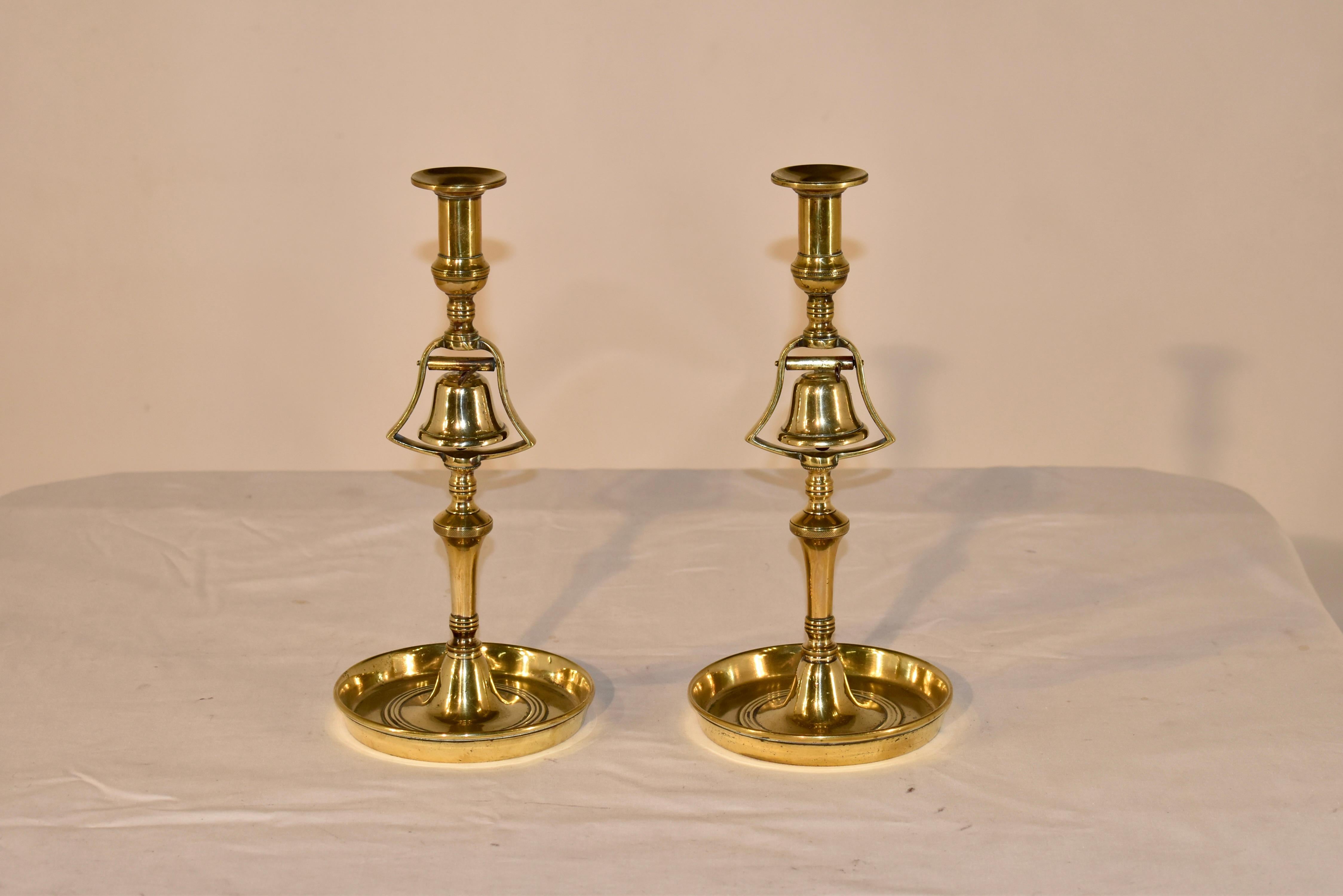 Unusual pair of Georgian brass tavern candlesticks with bells to ring for service.  This pair is wonderfully turned and have wide bobeches at the top of the stick and generous turnings throughout the stems.  The bells are absolutely wonderful and