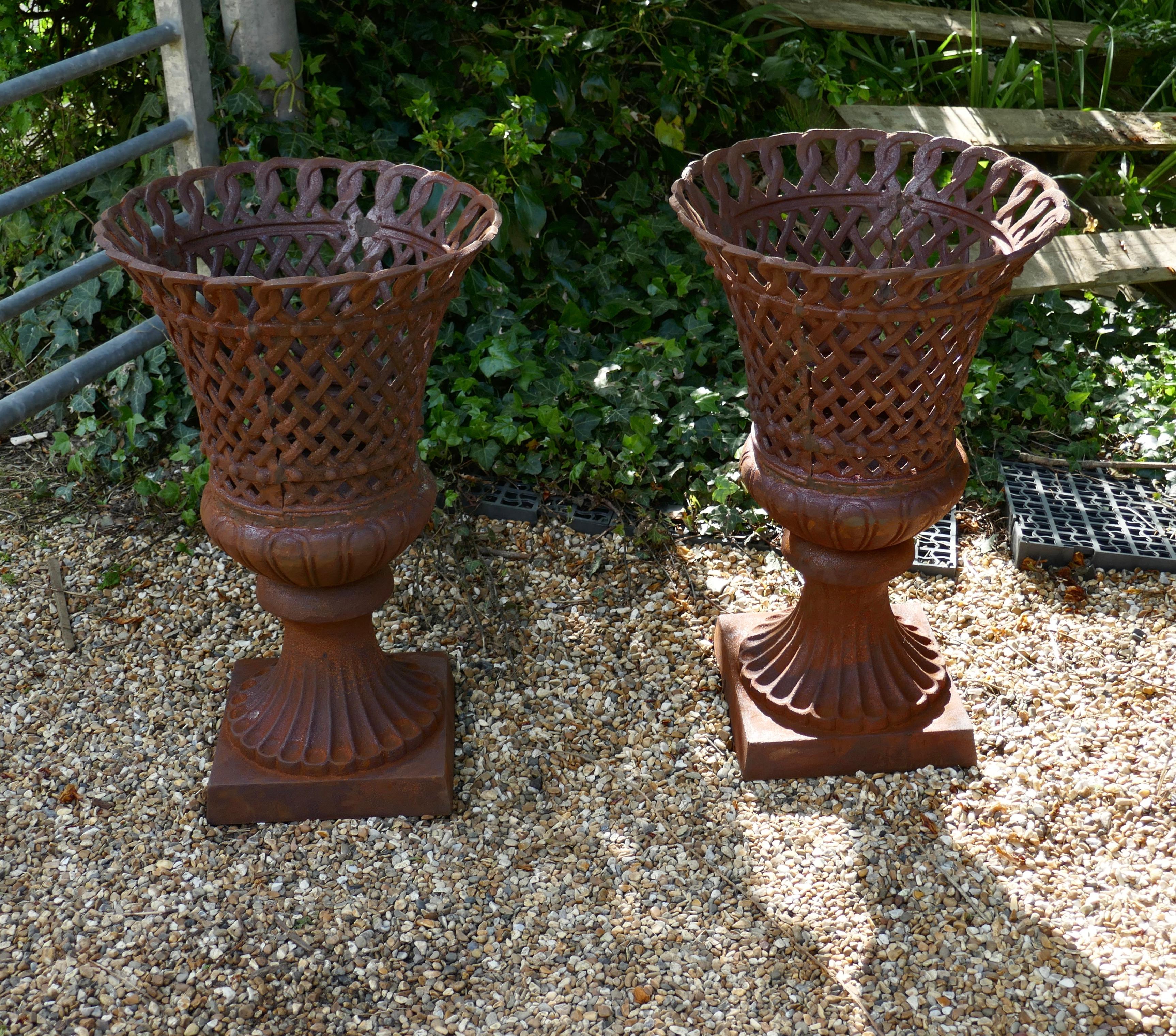 Unusual Pair of Lattice Work Cast Iron Garden Urns

This is a superb and unusual large pair of cast iron urns, they have an open work frame 
The urns are weather worn and have a rusty patina, they are otherwise in good condition 

The urns are