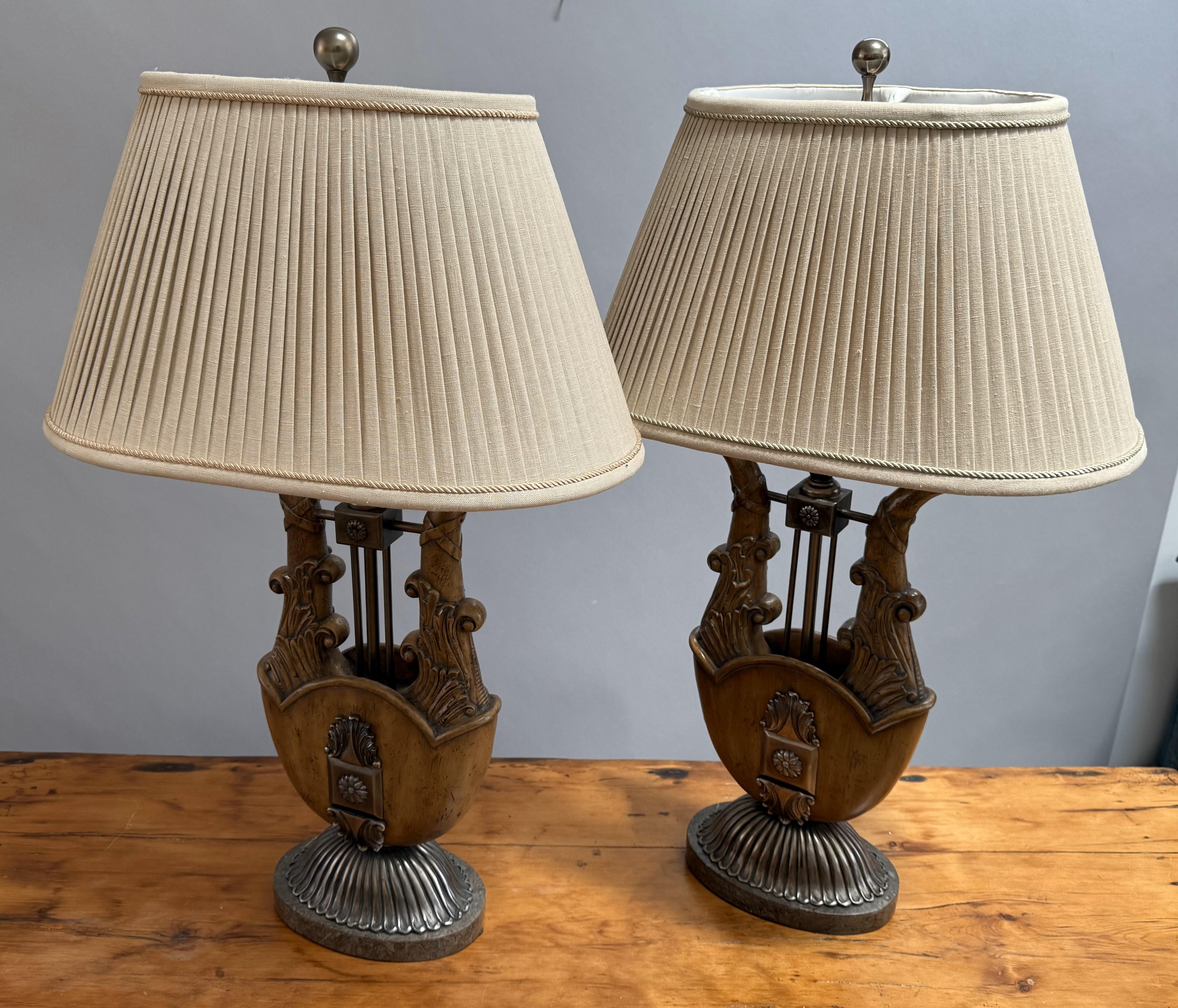 Unusual Pair of Neoclassical Lamps in the Form of a Lyre with Silver Mounts on Silver Oval Fluted Bases.

A striking pair of Neoclassical table lamps crafted in the form of classical lyres, mounted with silver-toned accents and resting on oval