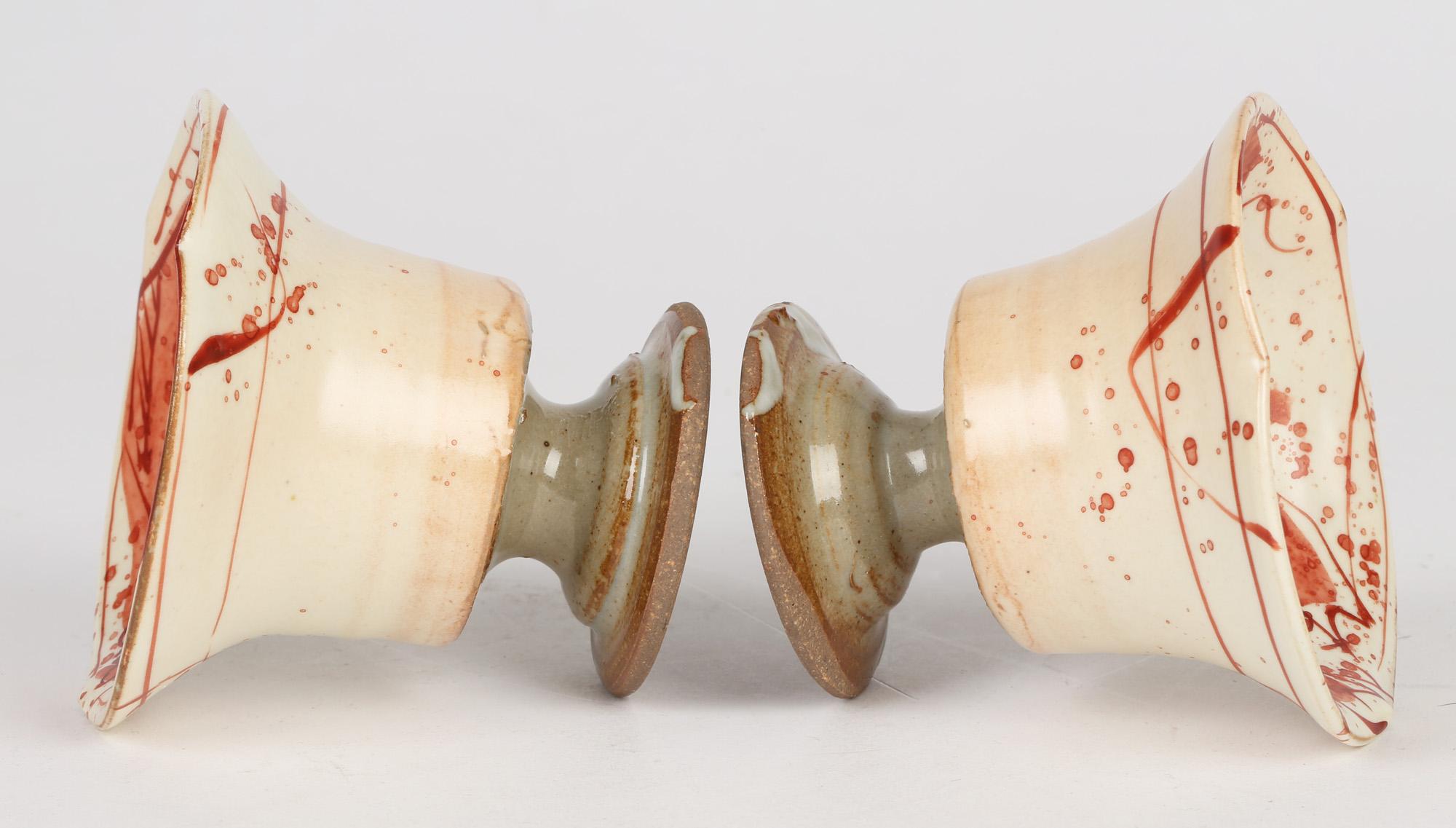 Une paire inhabituelle et intéressante de tasses à piédestal en poterie de studio peintes à la main avec des poissons et un crabe, probablement japonaises avec des marques de sceau imprimées et datant du 20e siècle. Les tasses reposent sur un pied