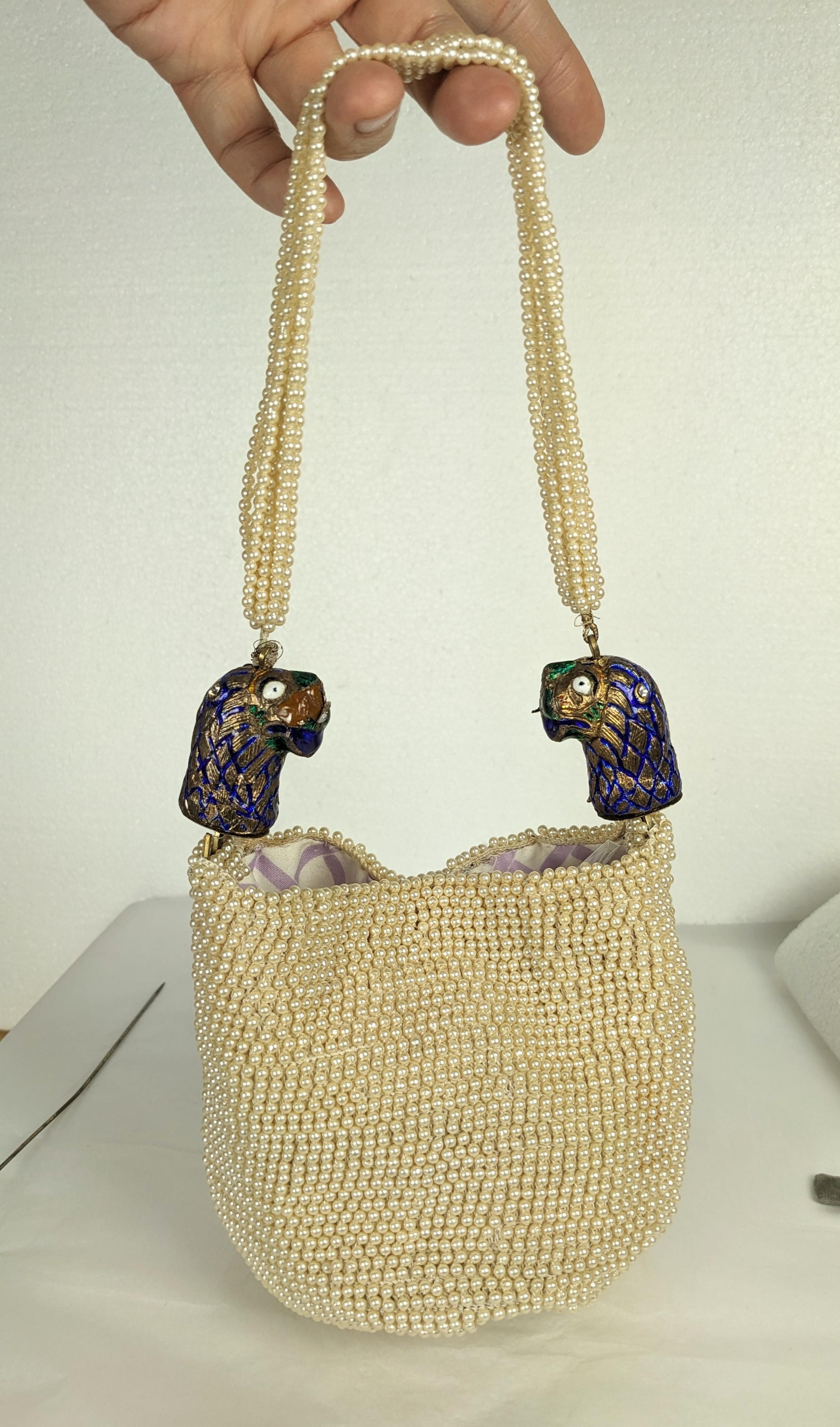Insolita borsa con perle finte degli anni '60 con finali d'epoca smaltati a testa di leone indiano. Forma a marsupio con una chiusura a scatto, la fodera è stata sostituita in un secondo momento. Manico di fili di perle multipli. 1960's. Altezza 5