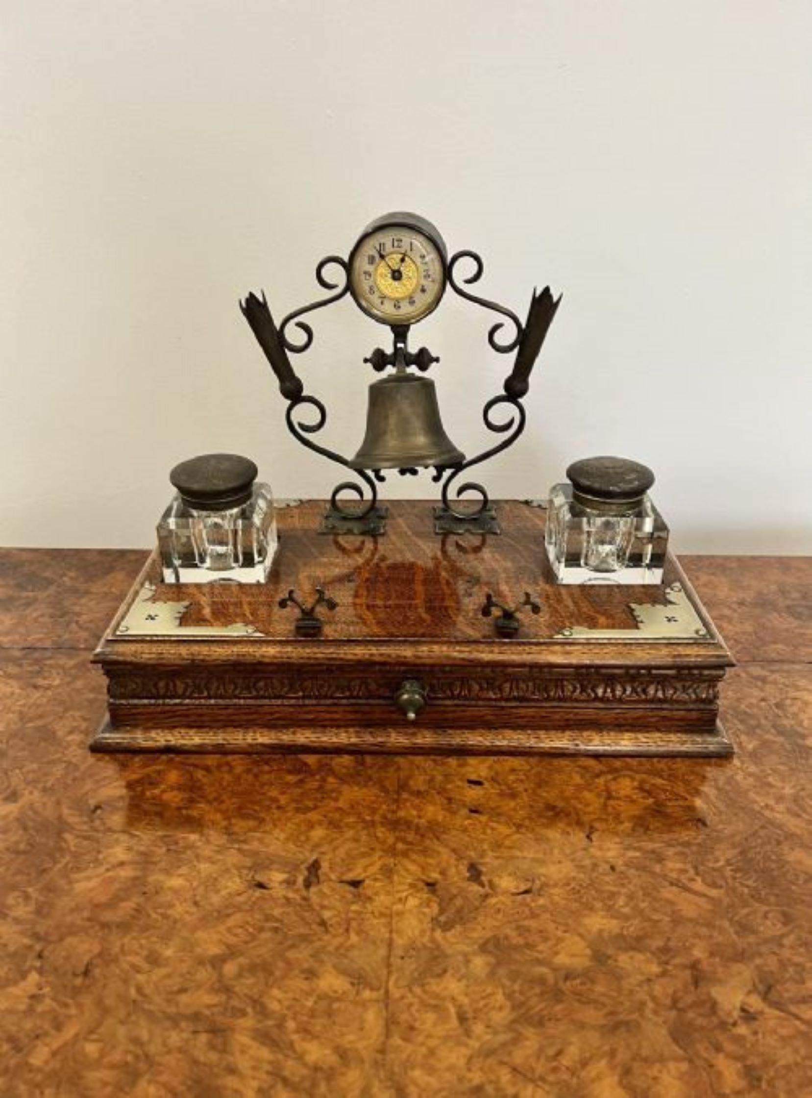 Unusual quality antique Victorian desk set having a quality shaped brass stand with a circular clock, bell and pen holders, above an oak base with silver plated corners and the original pair of removable glass inkwells to the front a carved oak
