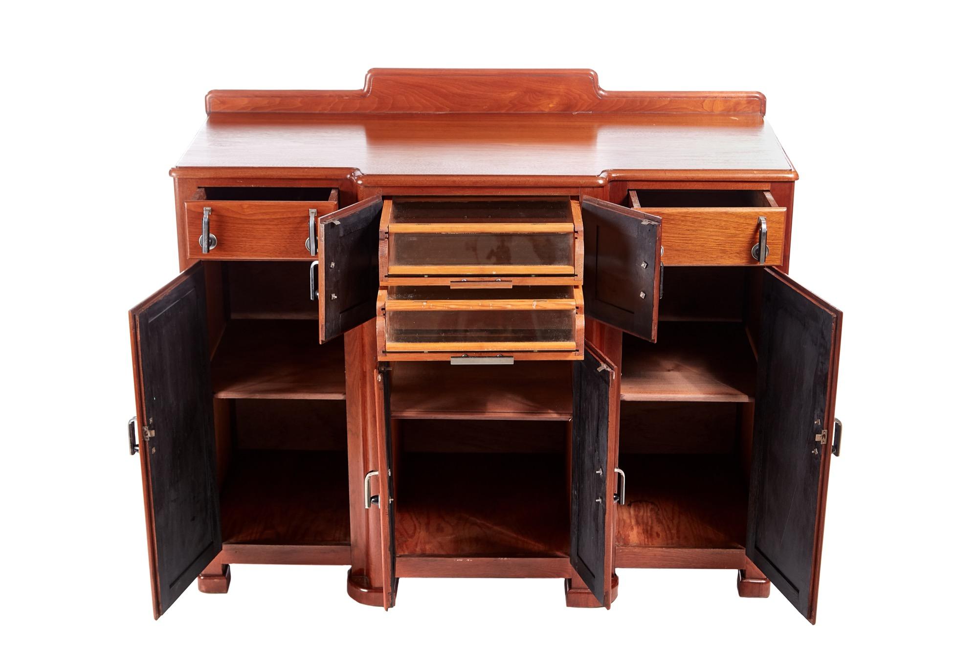 Unusual quality Art Deco walnut sideboard, small shaped back, lovely walnut top, 2 drawers to the frieze, 6 cupboard doors, fitted interior with 2 glass sliding drawers with original Art Deco handles, standing on shaped block feet.
Lovely color and