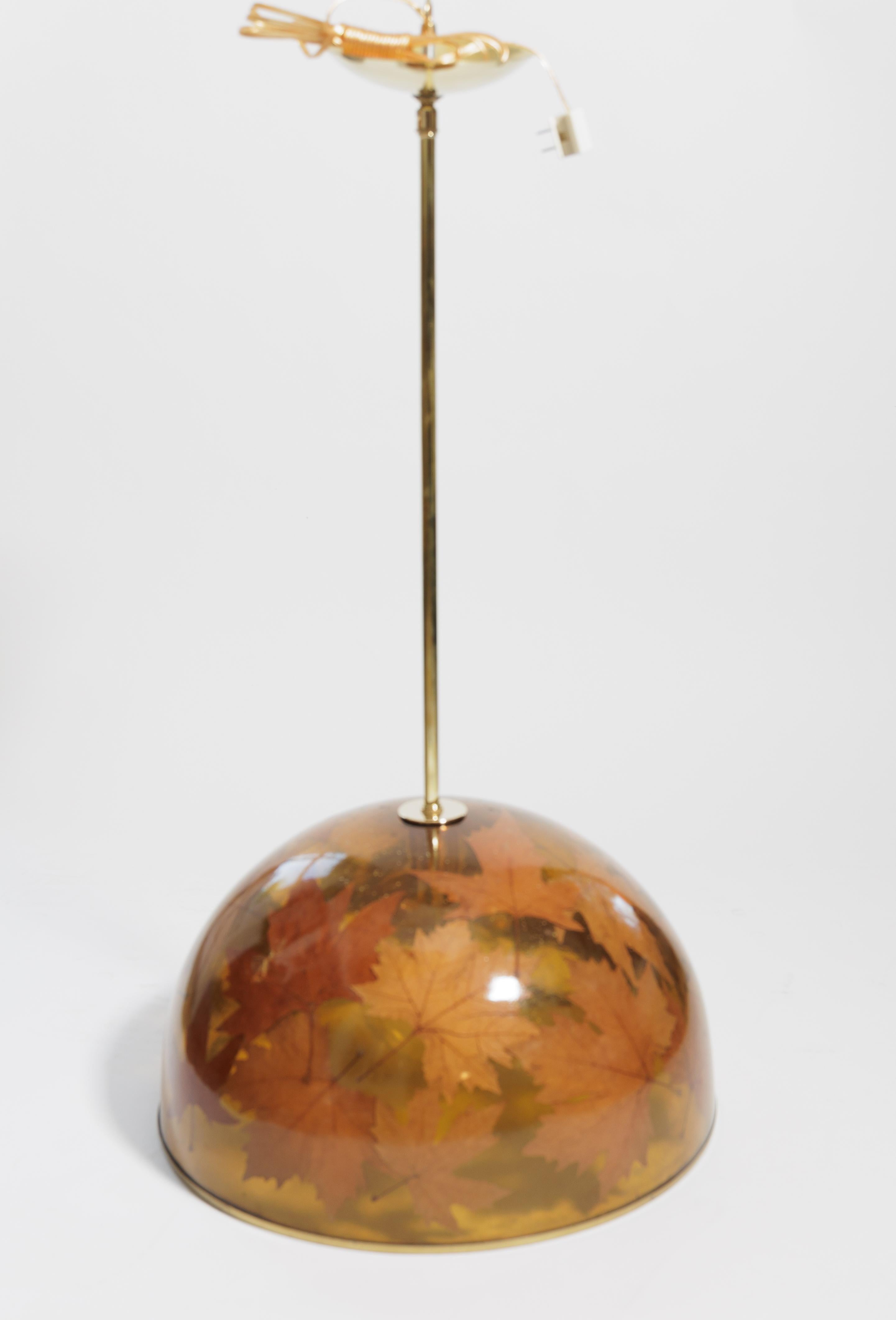 Pendentif en résine renfermant des éléments naturels (feuilles d'érable) avec des détails en laiton.
Deux sont disponibles.