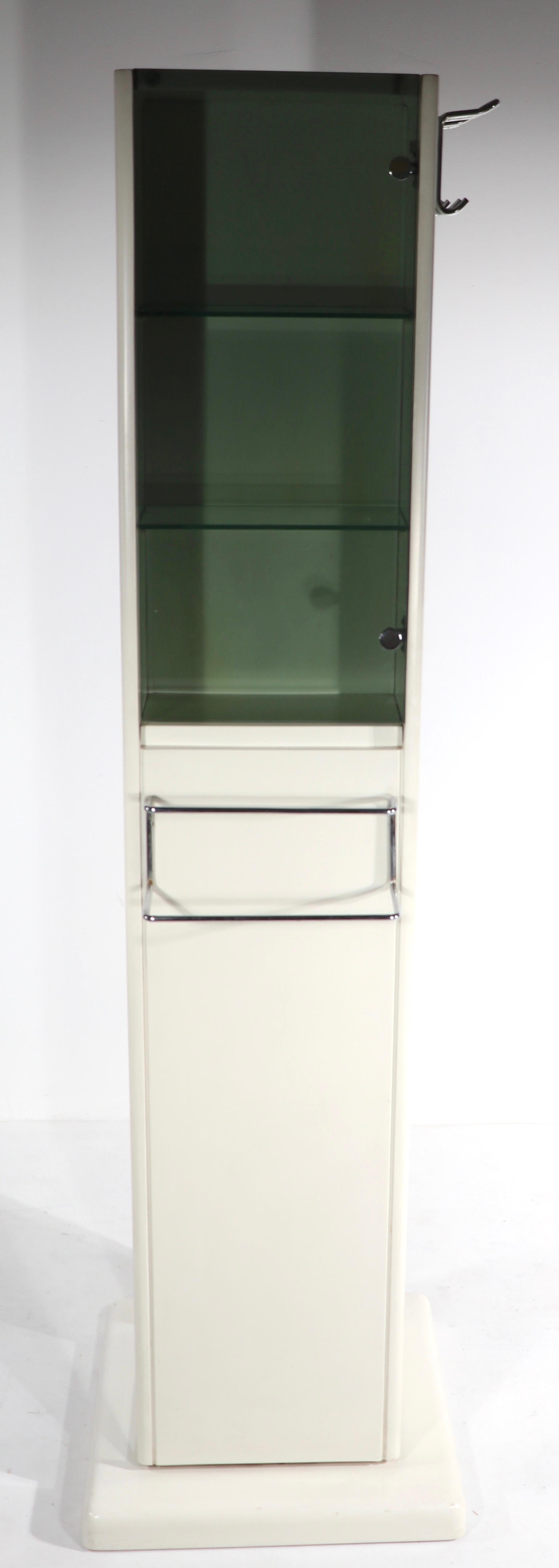Unusual revolving storage unit having tinted glass doors, drawers, a bread bin, and chrome hooks. The totem like center post rotates to allow easy access to the various storage bins. Done in the Italian Postmodern style, we believe it is actually