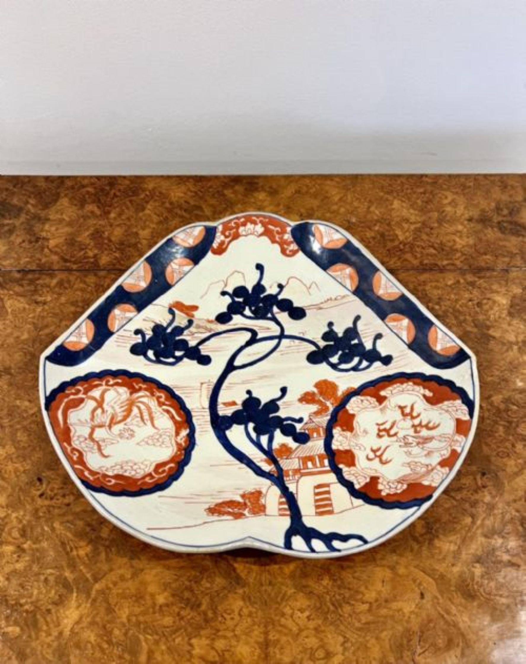 Unusual shaped antique Japanese Imari plate having an unusual shaped antique Japanese Imari charger having a scalloped shaped edge with hand painted detail with leaves, trees and a house hand painted in blue, red and white colours 