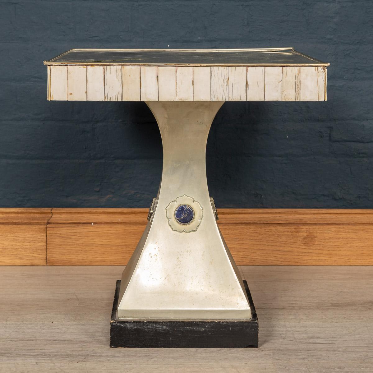 A bone and plated metal pedestal table by Anthony Redmile, mid-late 20th century, the top of square section with rectangular bone veneer plaques to the edges, on a square tapering pedestal applied with hardstone cabochons (most probably lapis