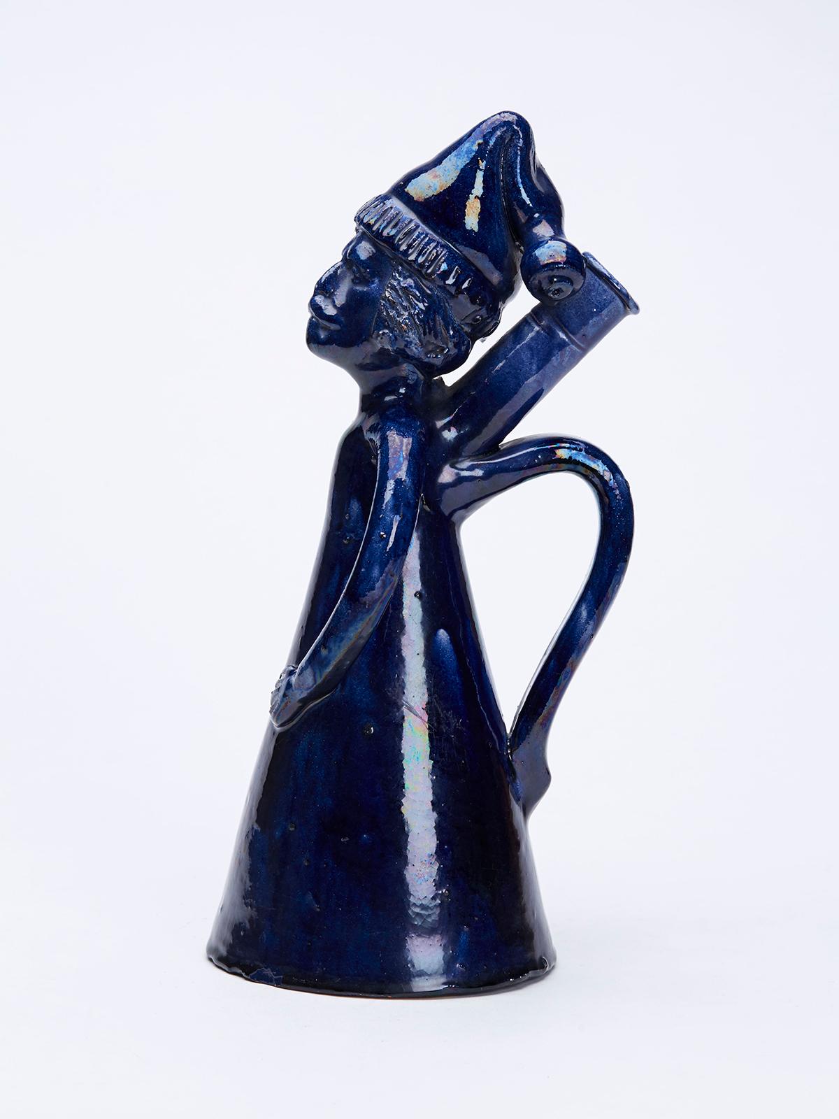 Inusual e interesante jarra o petaca antigua de cerámica roja esmaltada en azul folkart, con forma de hombre con camisón y gorro de dormir, del siglo XIX. La jarra tiene un ligero aspecto de rey medieval y está hecha a mano con un cuerpo en forma de