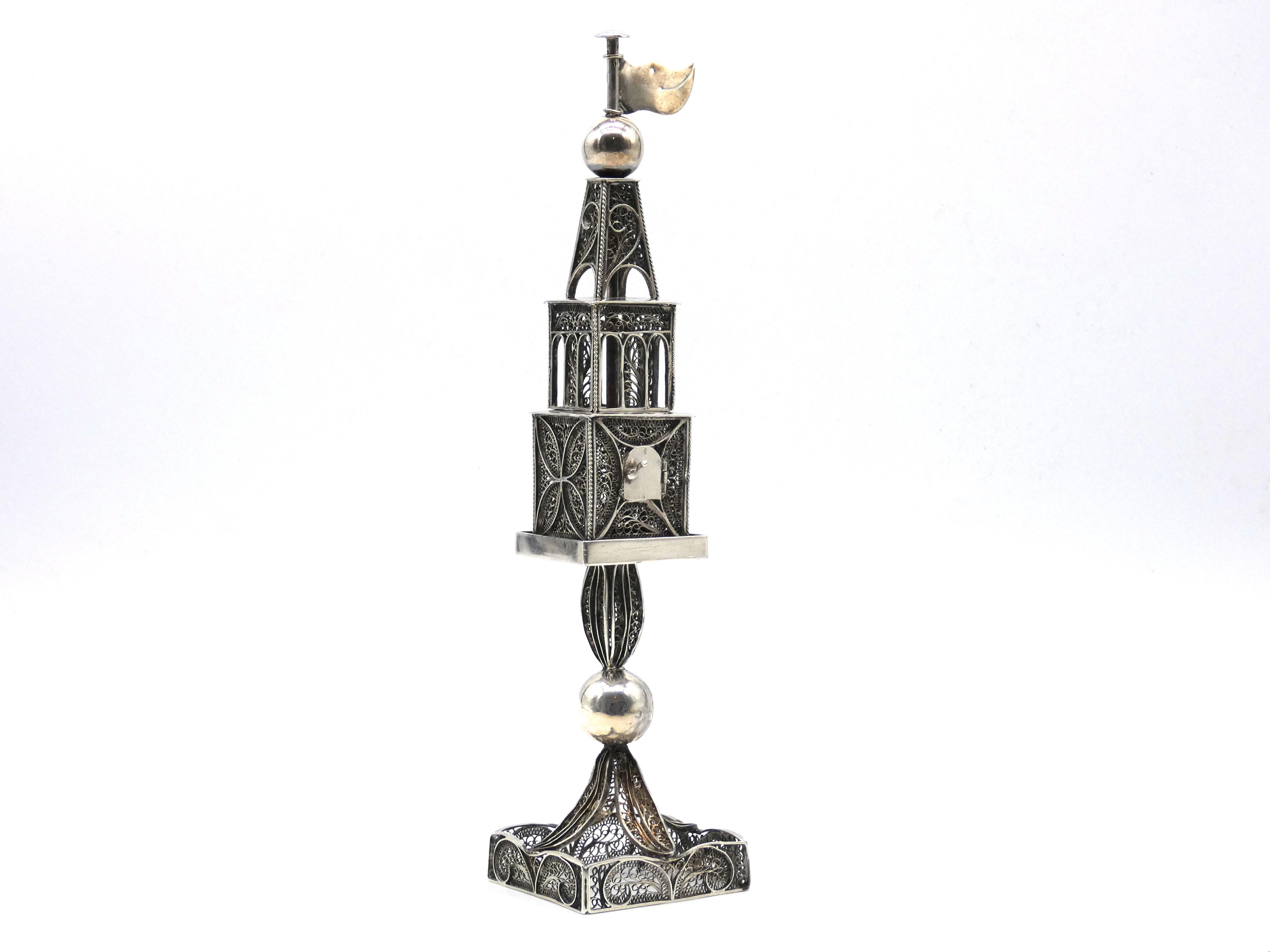 Spice tower has a square base with a filigree leaf designed stem branching upward and encompassed with a ball in center. Spice container is square shaped with a floral design in the filigree and has an arched shaped opening doorway for refilling the