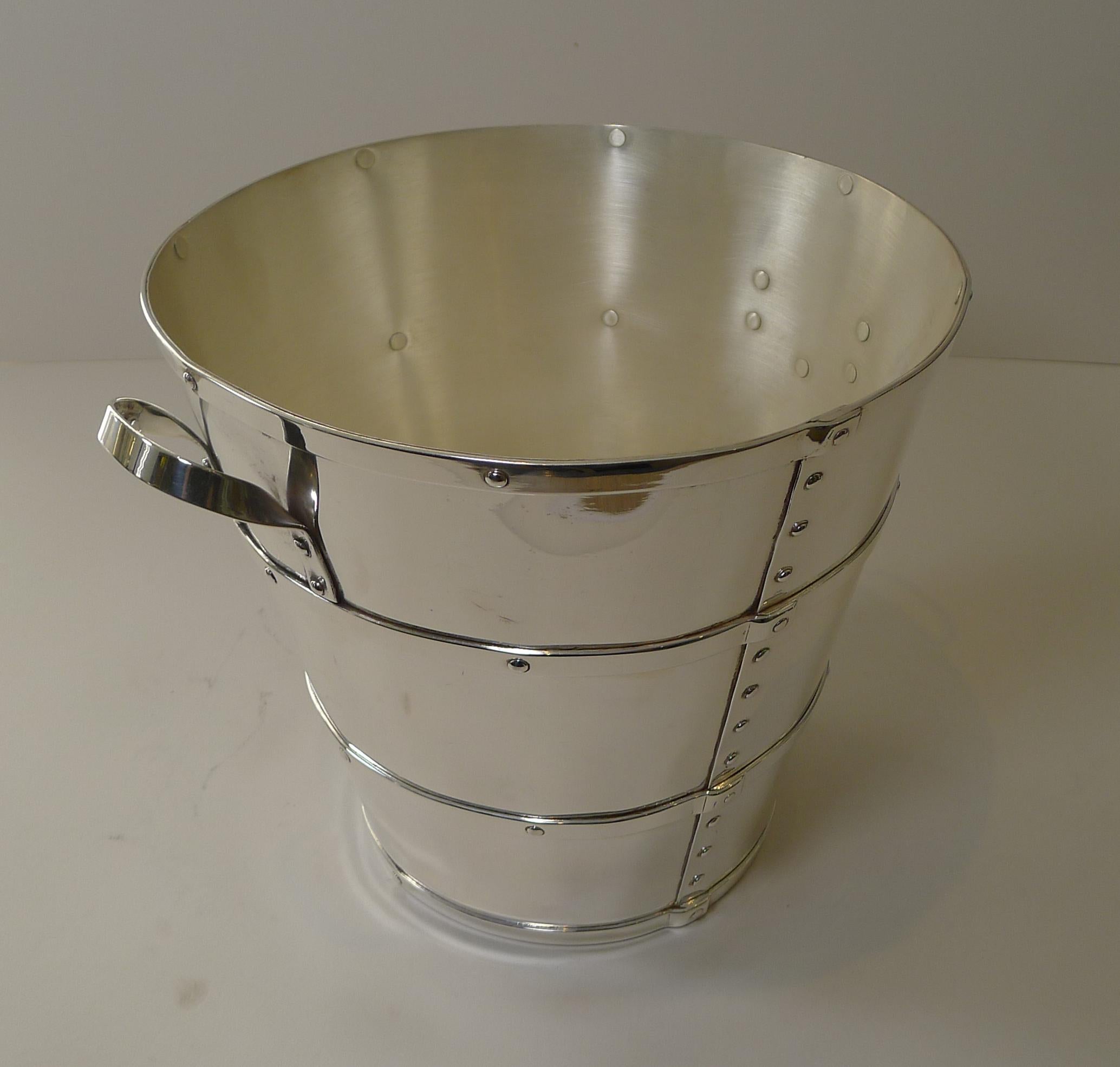 A magnificent and most unusual wine cooler or Champagne bucket made from silver plate and beautifully crated in the form of riveted leather bucket with handles, a great look, almost industrial in style.

The underside is fully marked for the