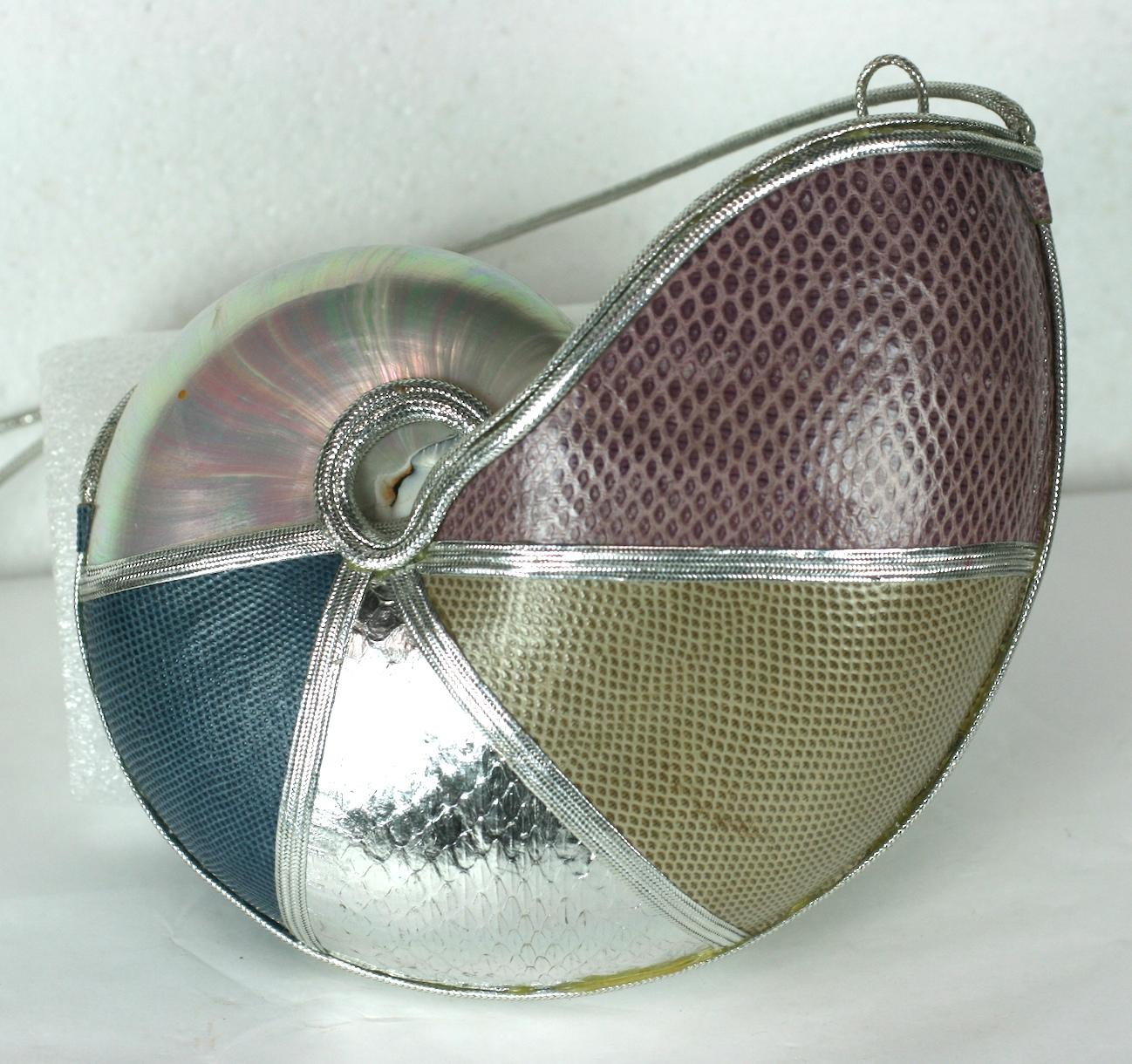 Unusual Nautilus Shell Purse clad in different panels of colored snakeskin in shades of rasberry, tan, teal and metallic silver which reflect the tones in the nacre of the shell. All the edges are covered in silver cording. Silver loop opens cover
