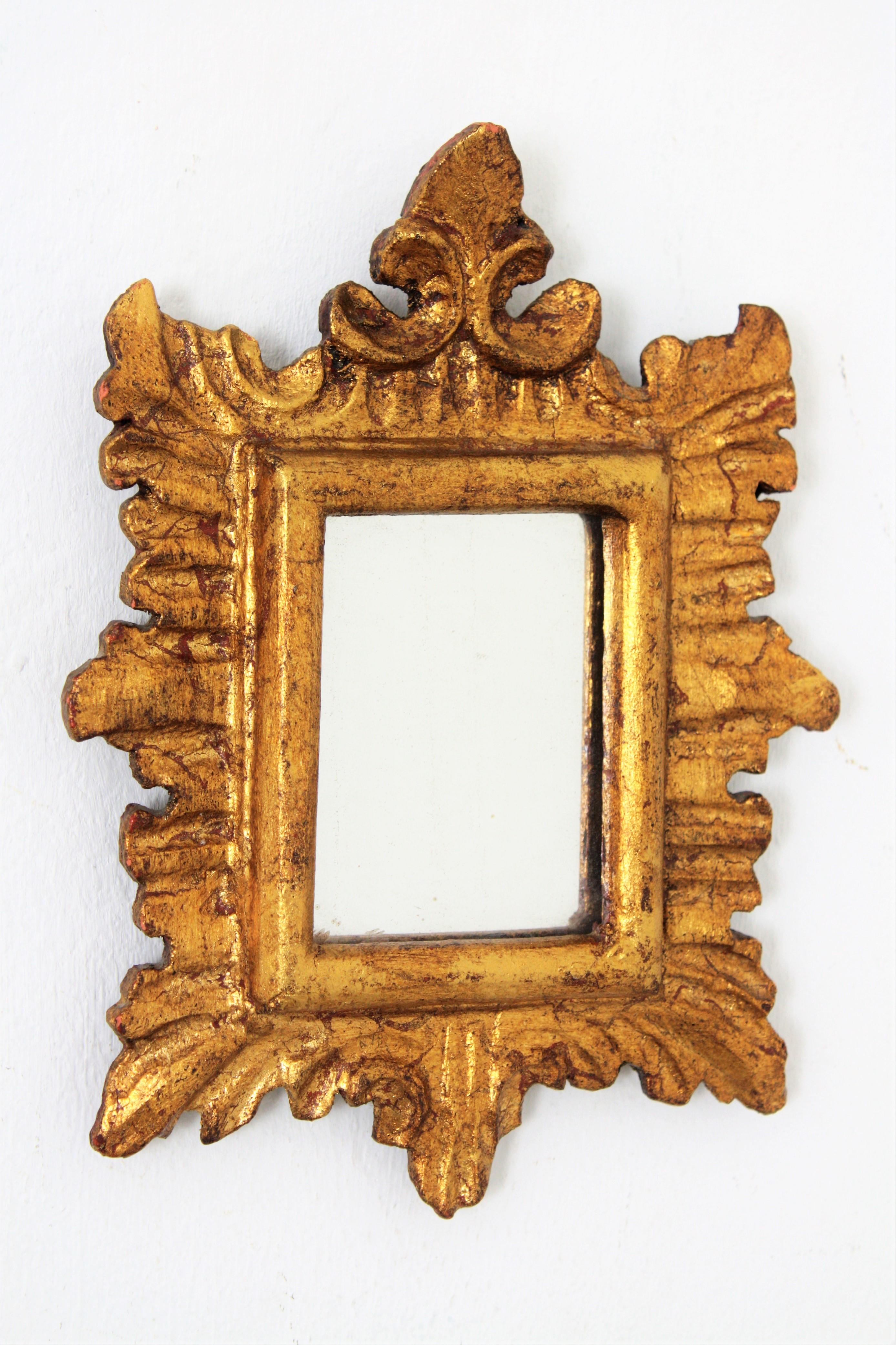 Unusual sunburst mirror miniature made of carved wood and finished with gold leaf. This piece, unusual due to its size, wears its original glass. It has been restored to preserve its original antique patina. It wears the manufacturer's label on the