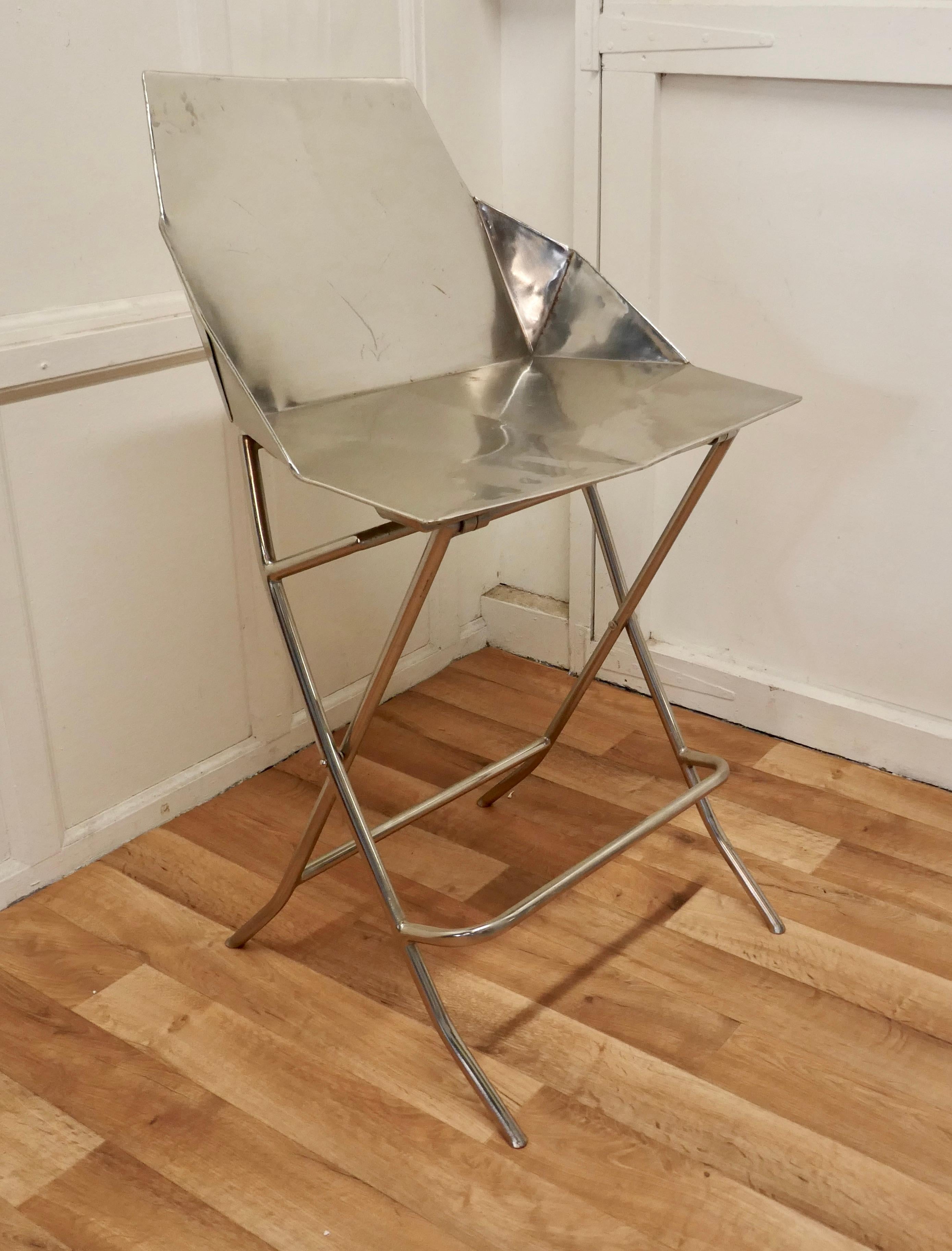 Unusual steel adjustable designer chair

A very unusual piece, this chair is all made in steel, the seat can be set to 2 different heights either to suit a bar or a table ( very handy for kitchen use)
The chair has a foot support rail, a flat