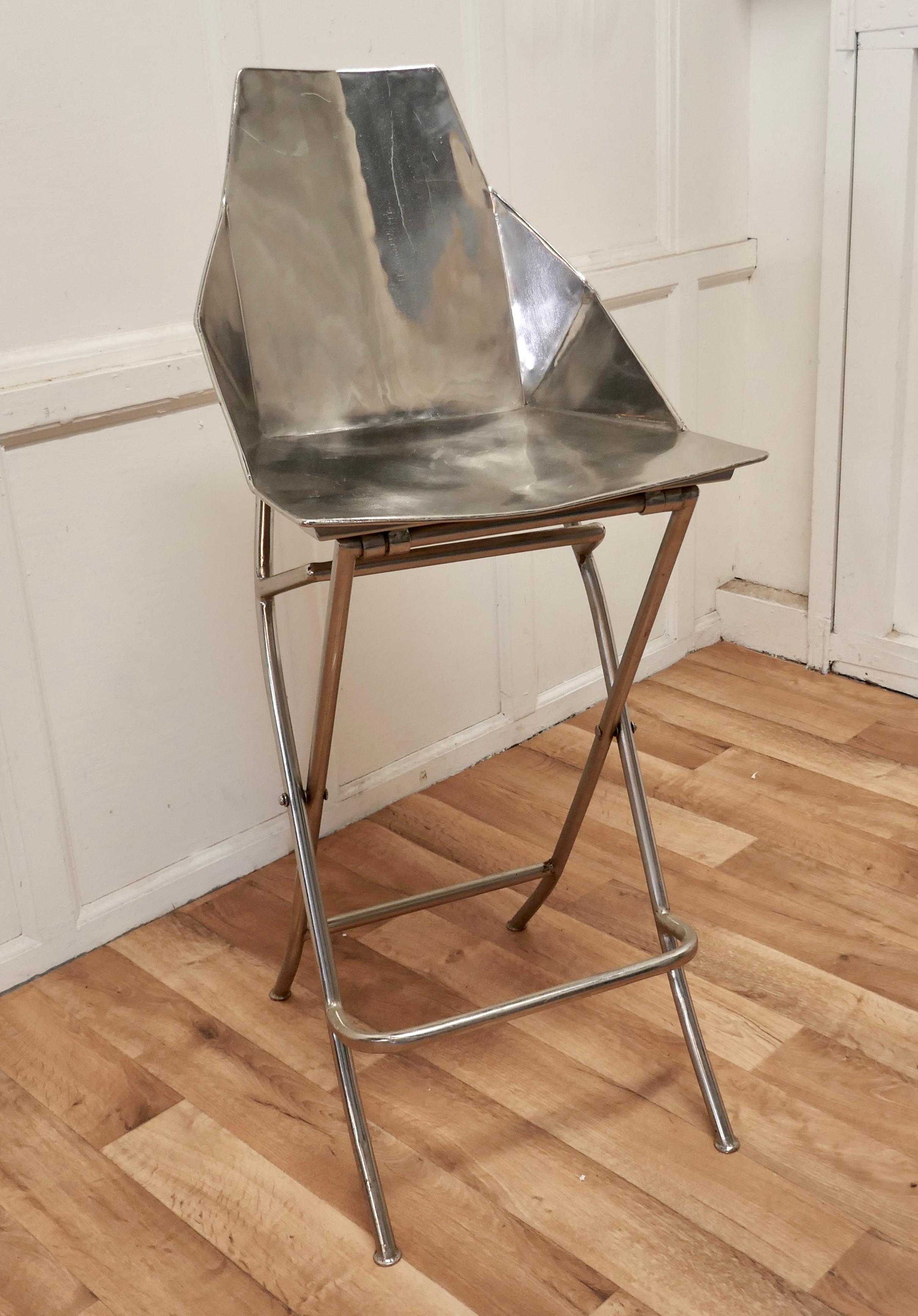 Unusual steel adjustable designer chair

A very unusual piece, this chair is all made in steel, the seat can be set to 2 different heights either to suit a Bar or a Table ( very handy for kitchen use)
The chair has a foot support rail, a flat