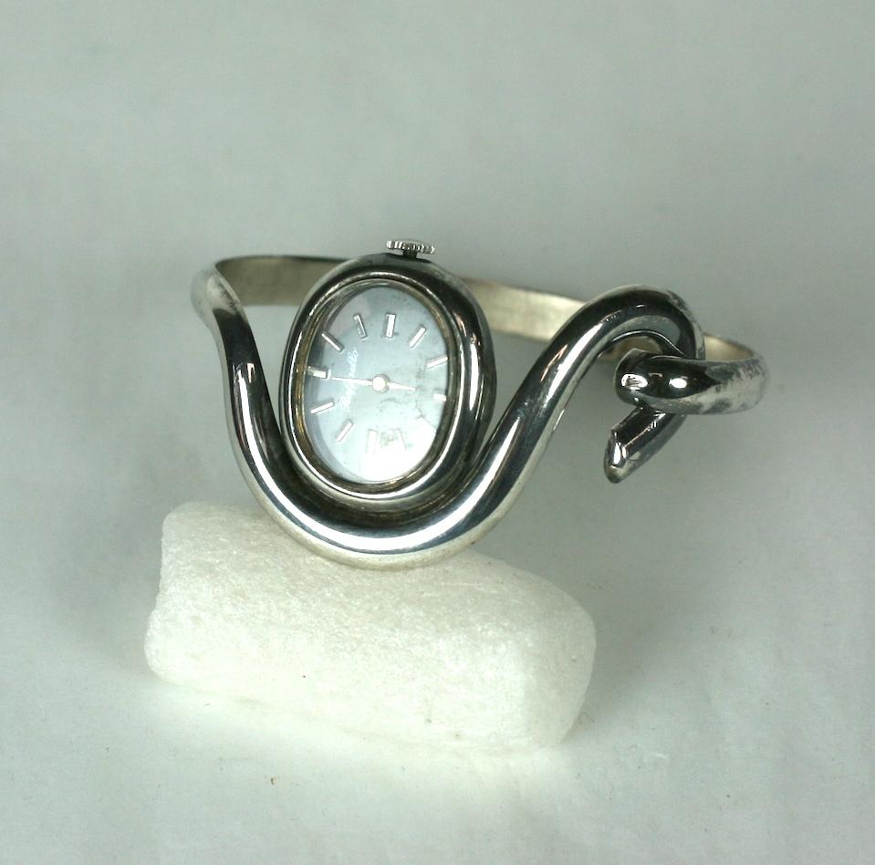 Unusual Sterling Modernist Clamper Watch from the 1970's. Hook Latch motif on hinged bangle with floating oval watch inserted into design. Small size. 
Watch works when wound. Face 1
