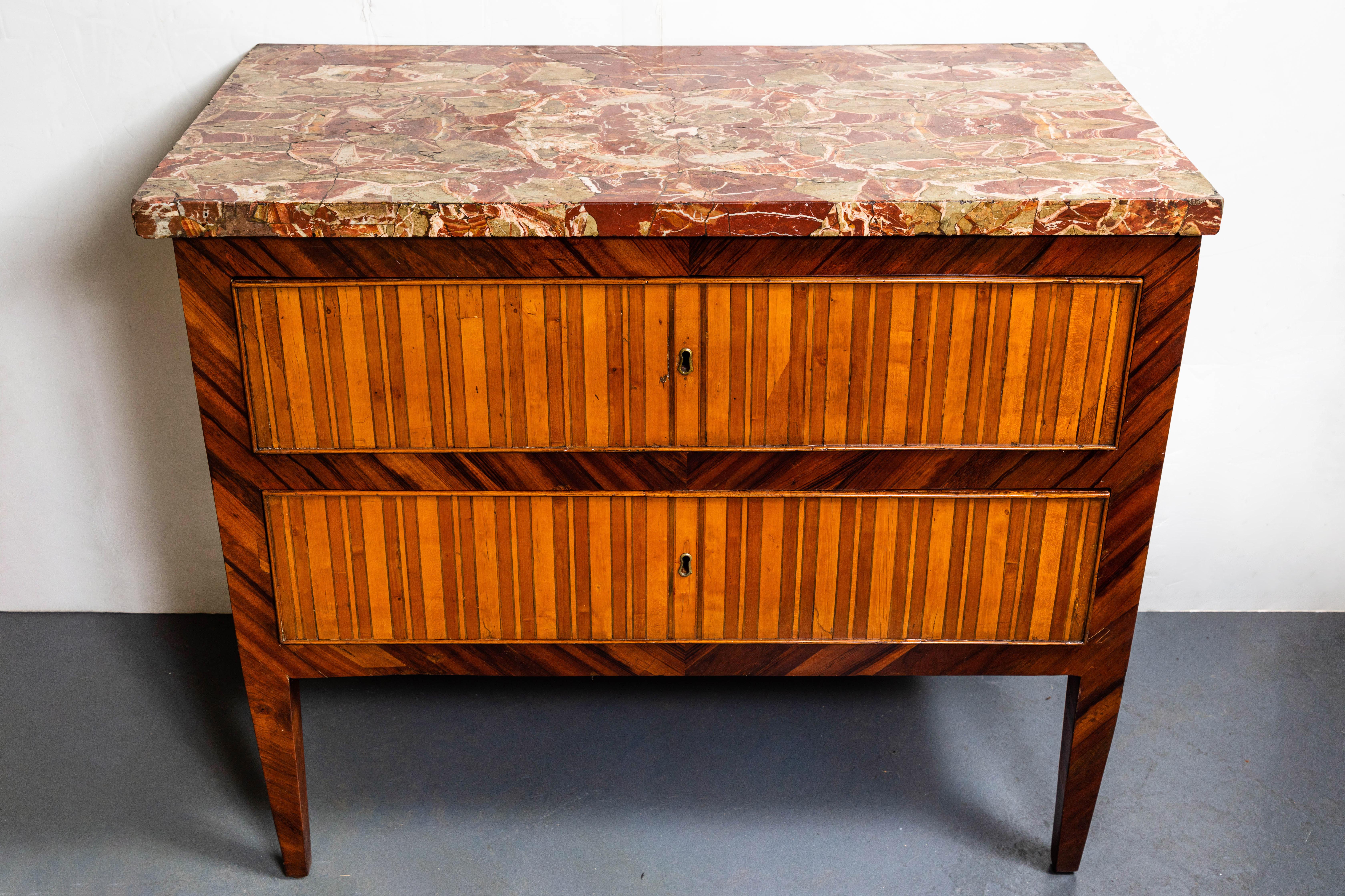 Rare and wonderful, 18th century, two-drawer commode from Genoa featuring four panels of fabulous striping in pear, walnut, and fruit woods. The whole on tapered legs and surmounted by a lush, original, now extinct, rouge marble slab.
