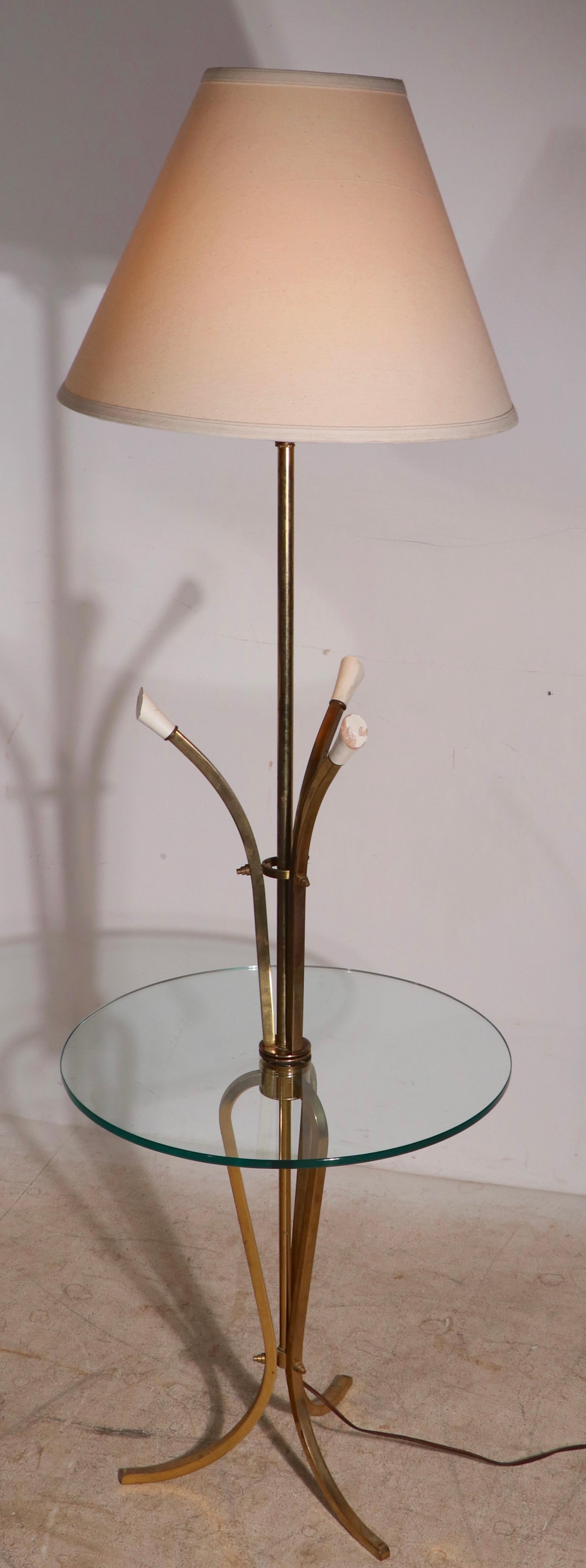 Voguish floor lamp with circular plate glass table attached. The vertical elements are of squared brass, the tops terminate in stylized wood flowers, in original white paint finish.
Quintessential Hollywood Regency floor lamp, in very fine,