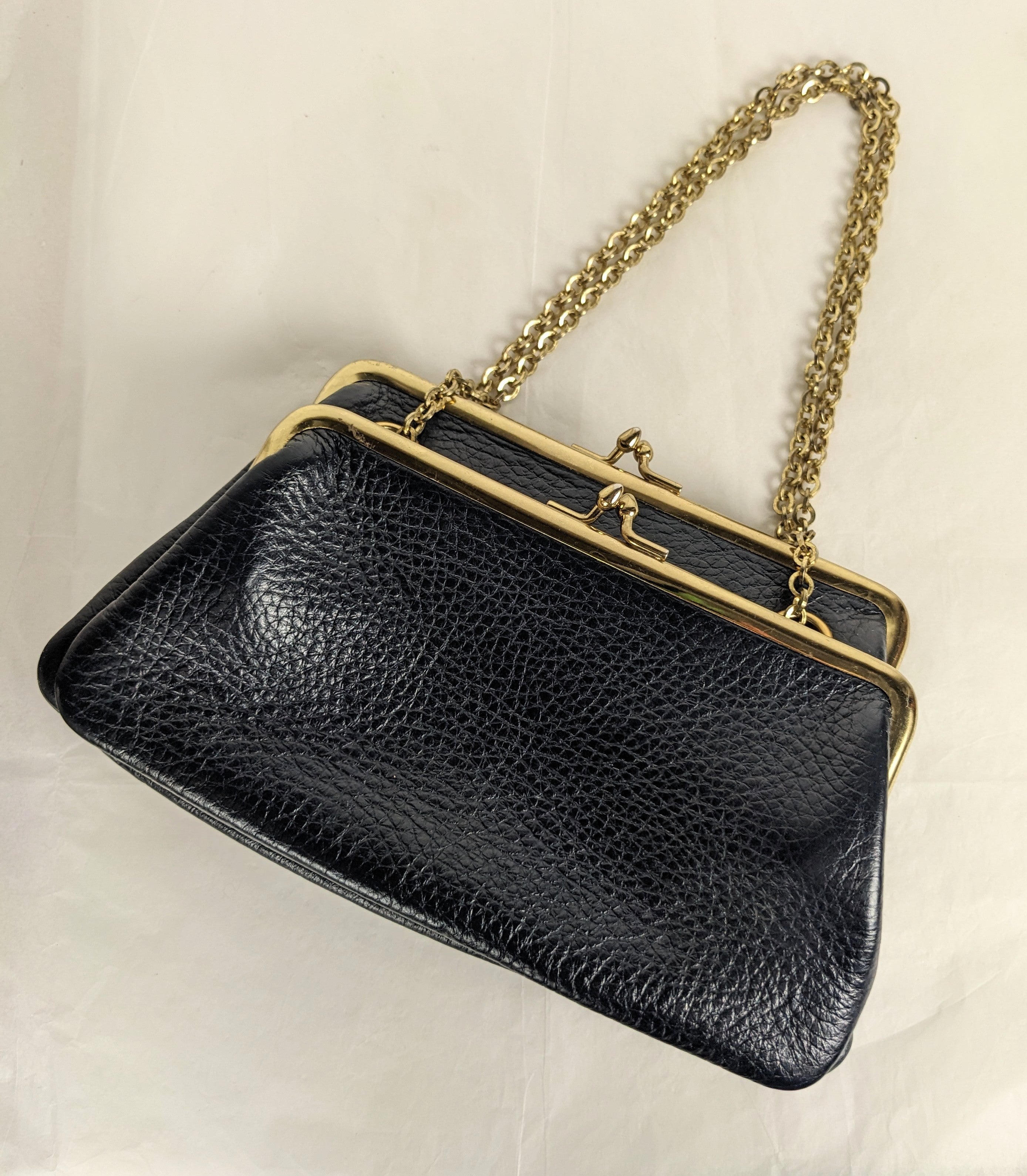 Charmant et inhabituel sac en cuir marbré à triple fermeture à baiser, de couleur bleu marine. Poignée en chaîne transformable pour une utilisation à la main ou à l'épaule. 2 pochettes latérales sont attachées à un compartiment principal, toutes