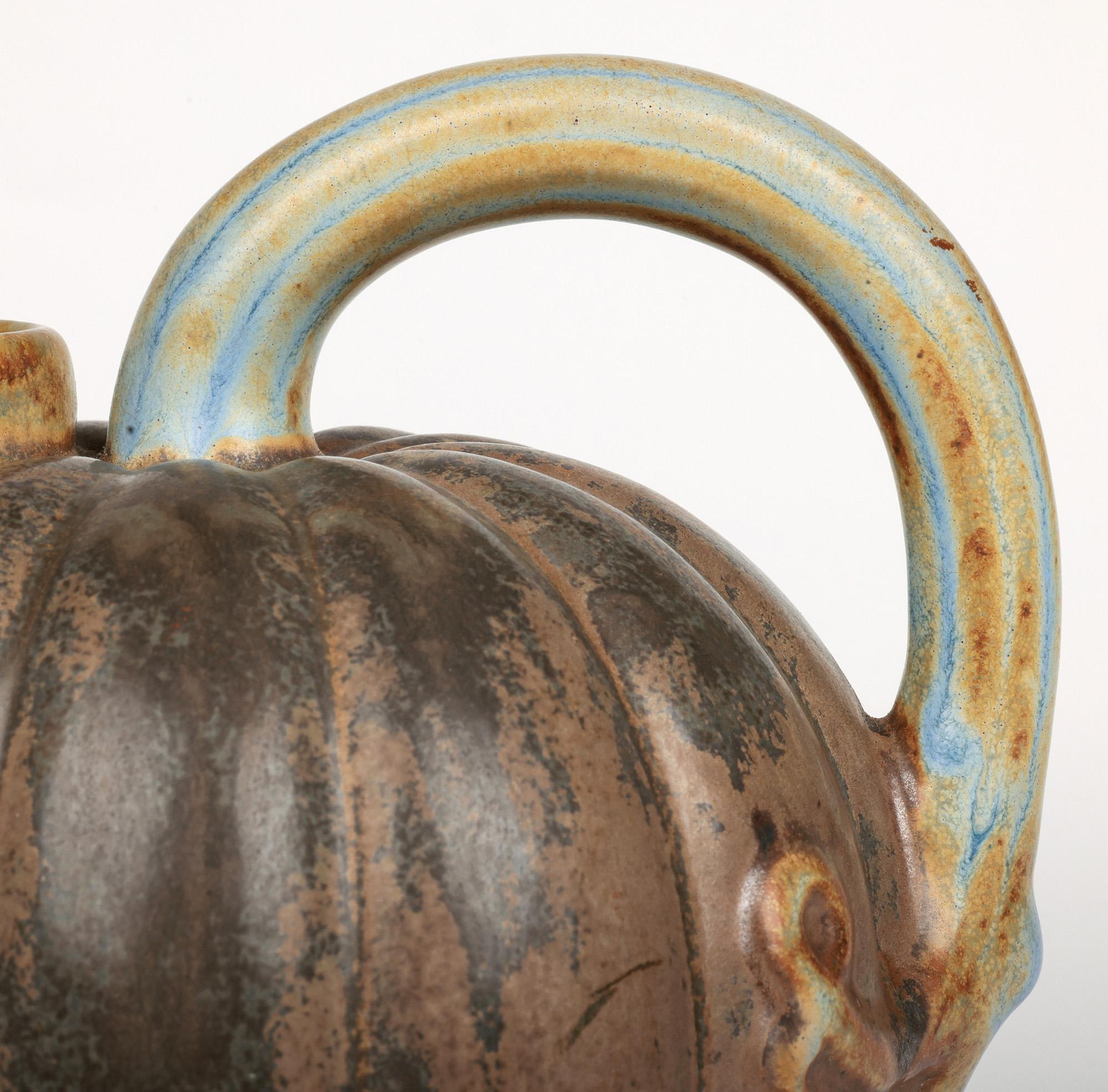 Une superbe cruche en poterie d'art à glaçure striée en forme de melon, probablement scandinave et datant du milieu du siècle dernier ou d'avant. La cruche en grès repose sur un pied étroit et rond non émaillé. Le corps est de forme ronde et