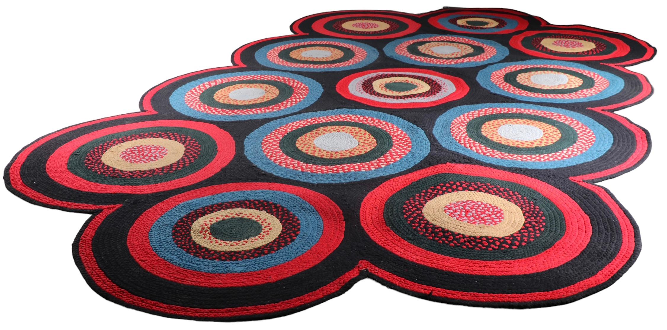 Incredible room size braided rug featuring repeating disks of expanding concentric rings of polychrome fabric on a  black background. While this is a country style rug, its bold, graphic and geometric pattern makes it suitable for a more modern