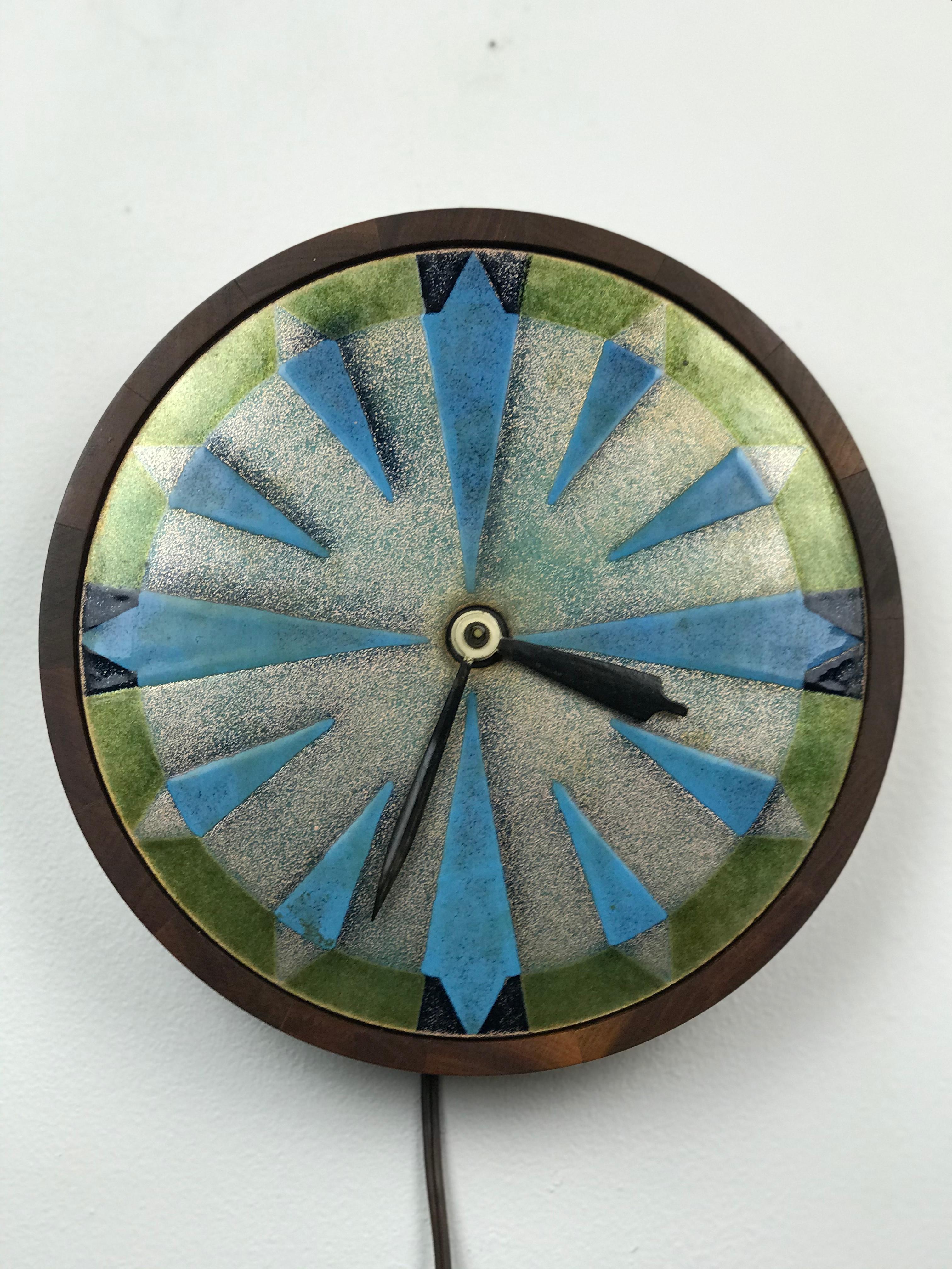 Scarce midcentury wall clock in painted enamel on copper with a thick walnut case by Judith Daner, 1960s. The clock works nicely and keeps accurate time. Changing to a battery mechanism can be done quickly if you prefer. Nice silver/green/blue hues.