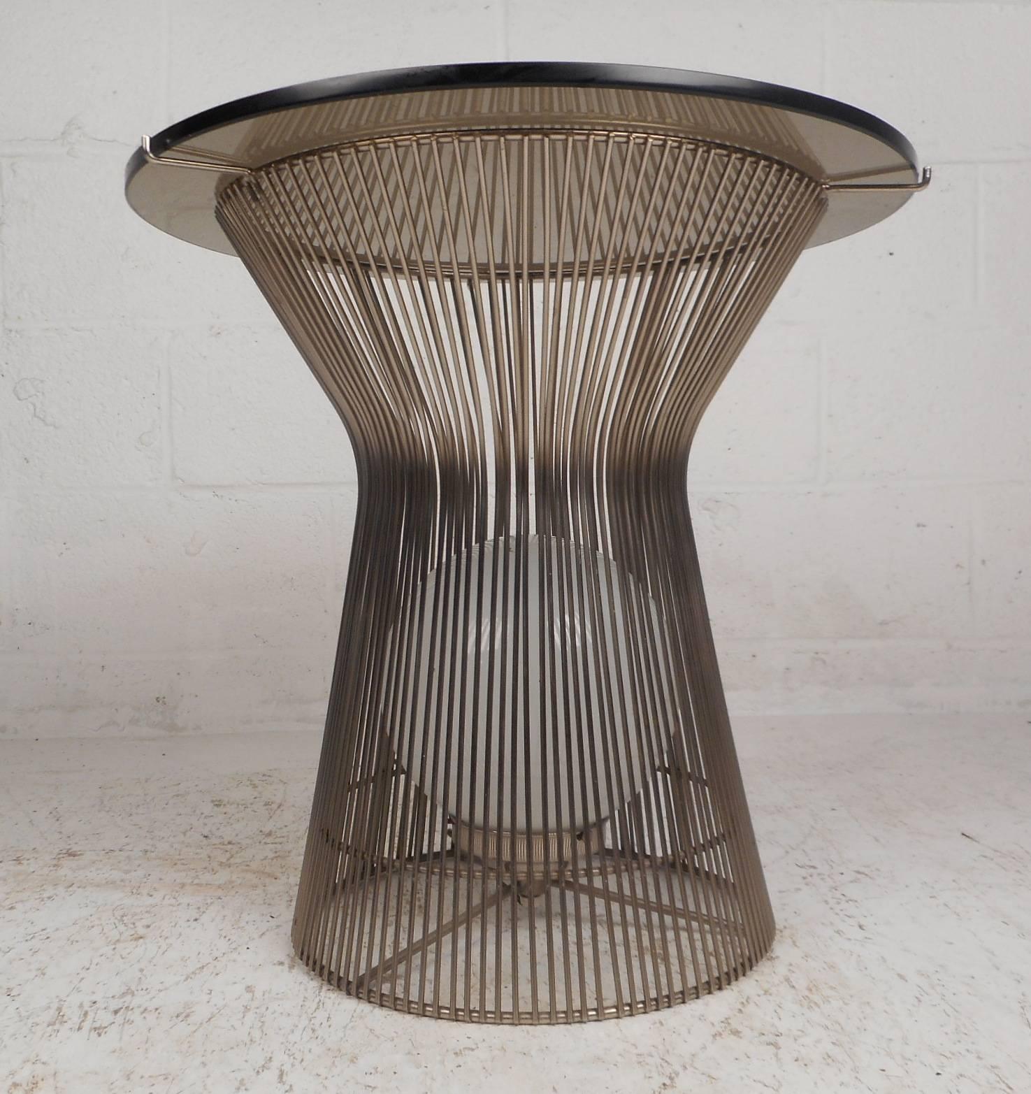 This fabulous Mid-Century Modern end table features an hourglass shaped wire rod frame with a large light bulb inside and a round smoked glass top. This multifunctional vintage modern table is sure to add style and grace to any modern interior.