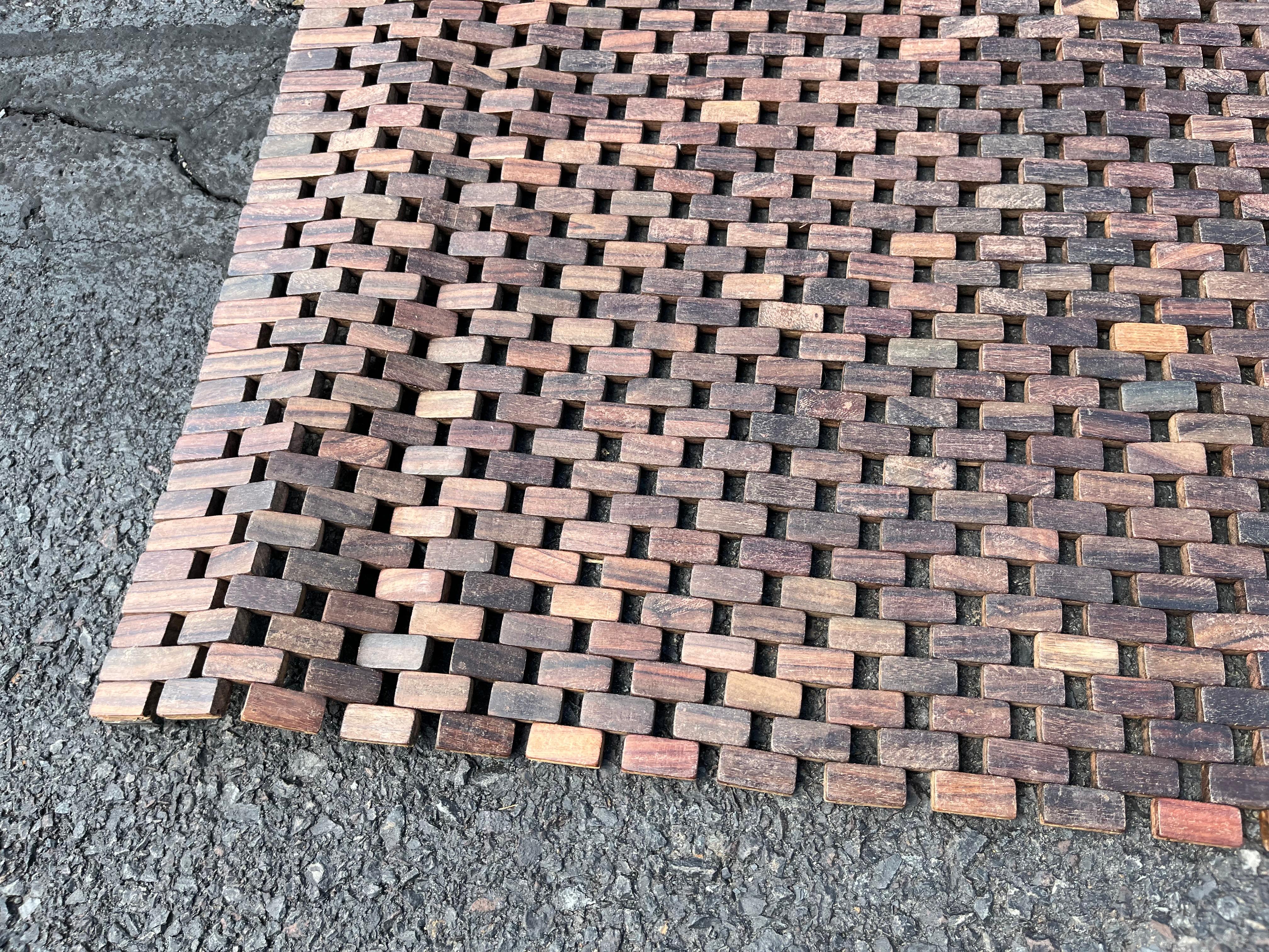An unusual floor covering made from thousands of tiny teak blocks strung together with wire.