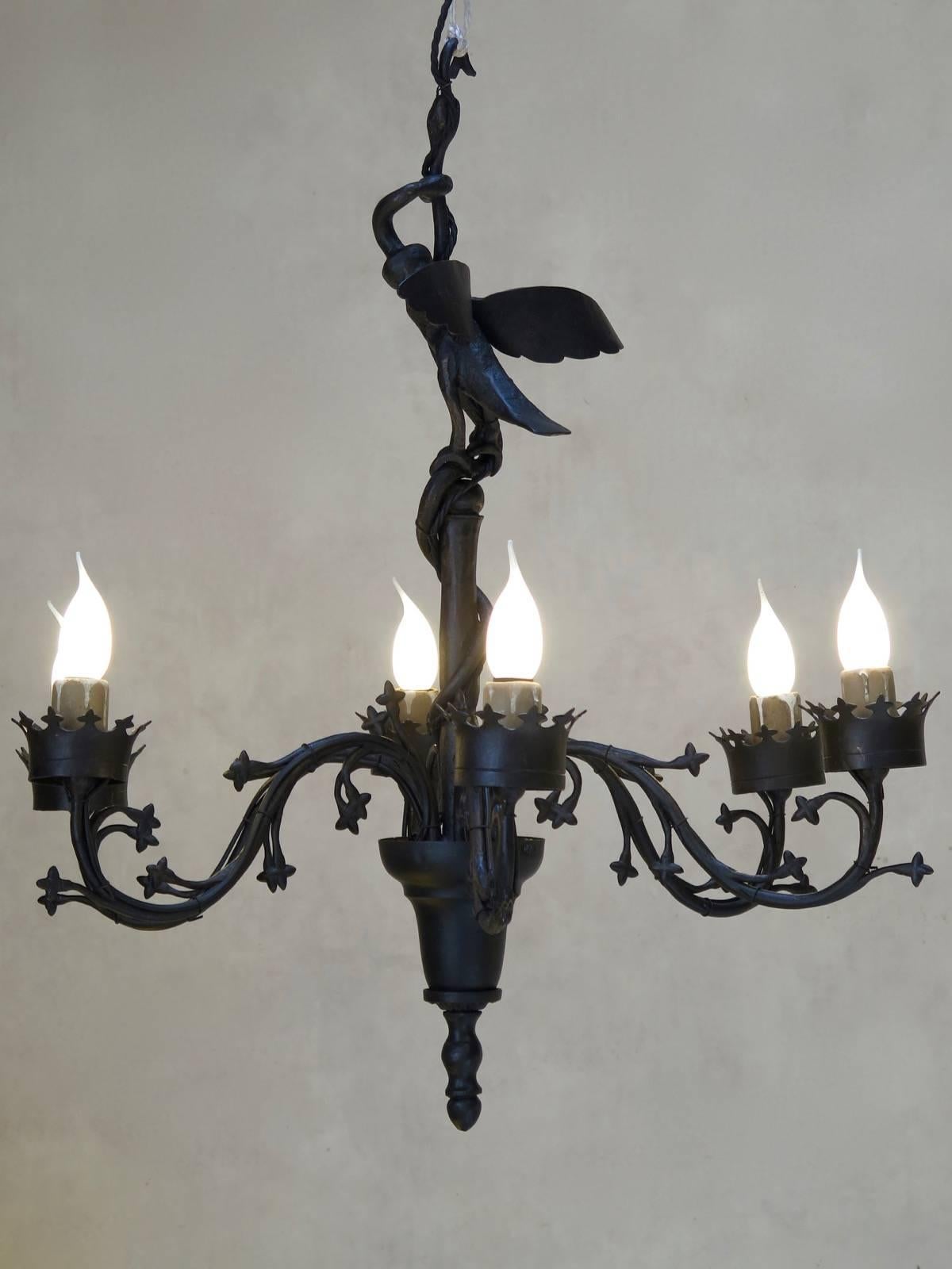 An unusual, neo-Gothic style, eight-arm chandelier, representing a bird with wings deployed, with a snake coming out of its body, and eating another snake. The serpent's tail twists around the central shaft of the chandelier. The bobeches are