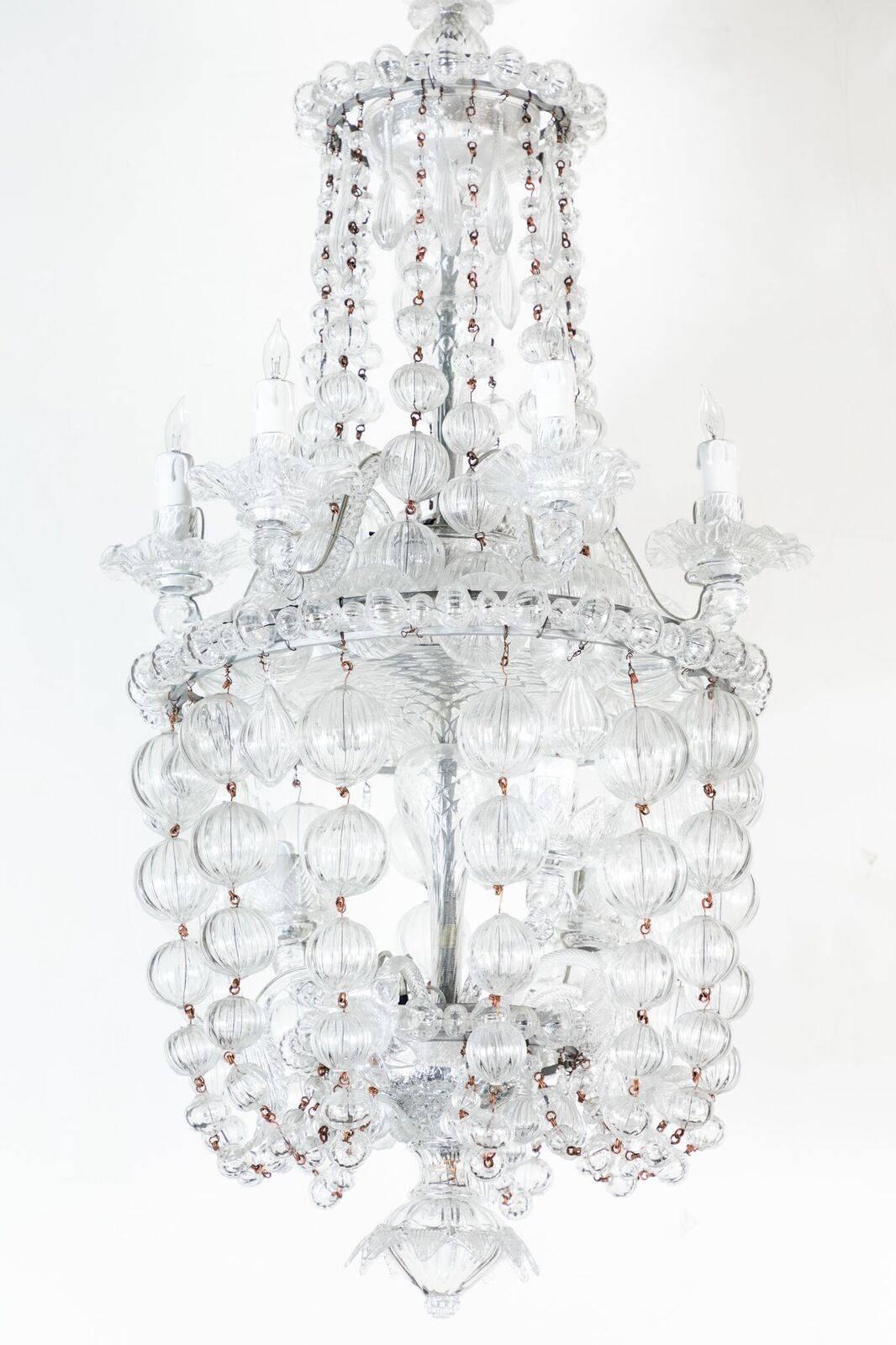 Elegant, Murano glass chandelier with a rare and appealing shape, featuring two tiers of cascading strands of lobed, glass spheres between a circle of six lights. Three more bulbs illuminate the interior.