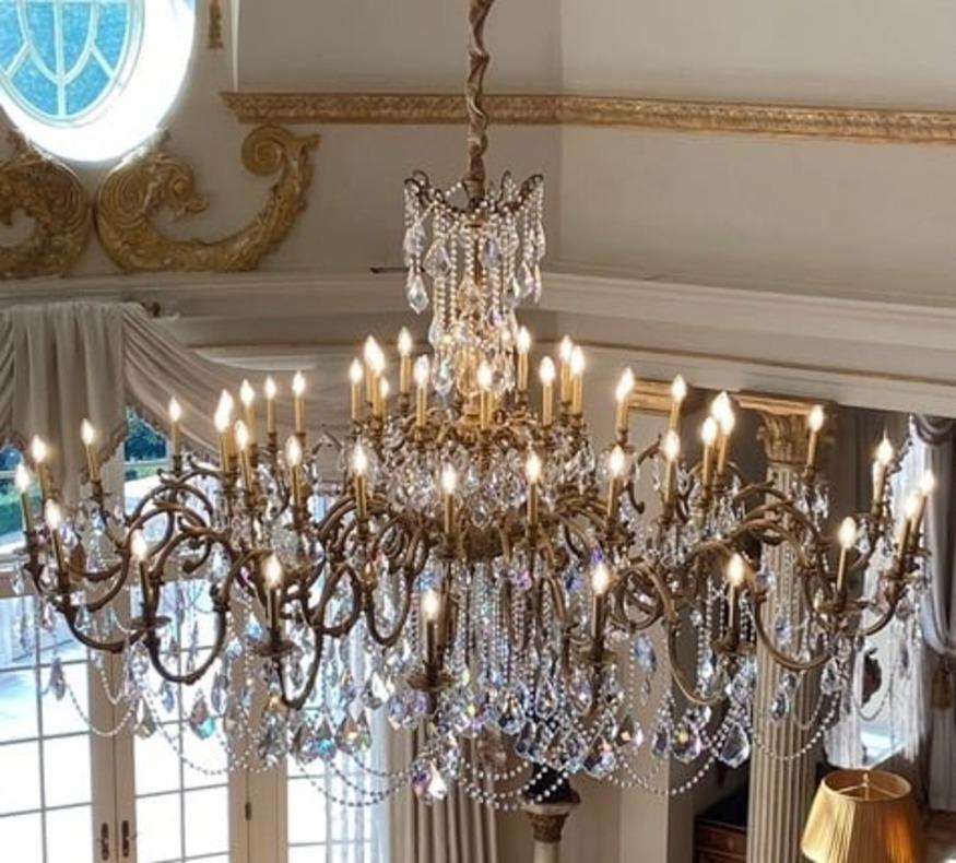 Lustre à trente-trois lumières en bronze et verre taillé d'une taille inhabituelle
avec des bras à double enroulement supportant chacun deux bougies, la tige donnant naissance à d'autres bougies, le tout suspendu à des chaînes en verre taillé avec