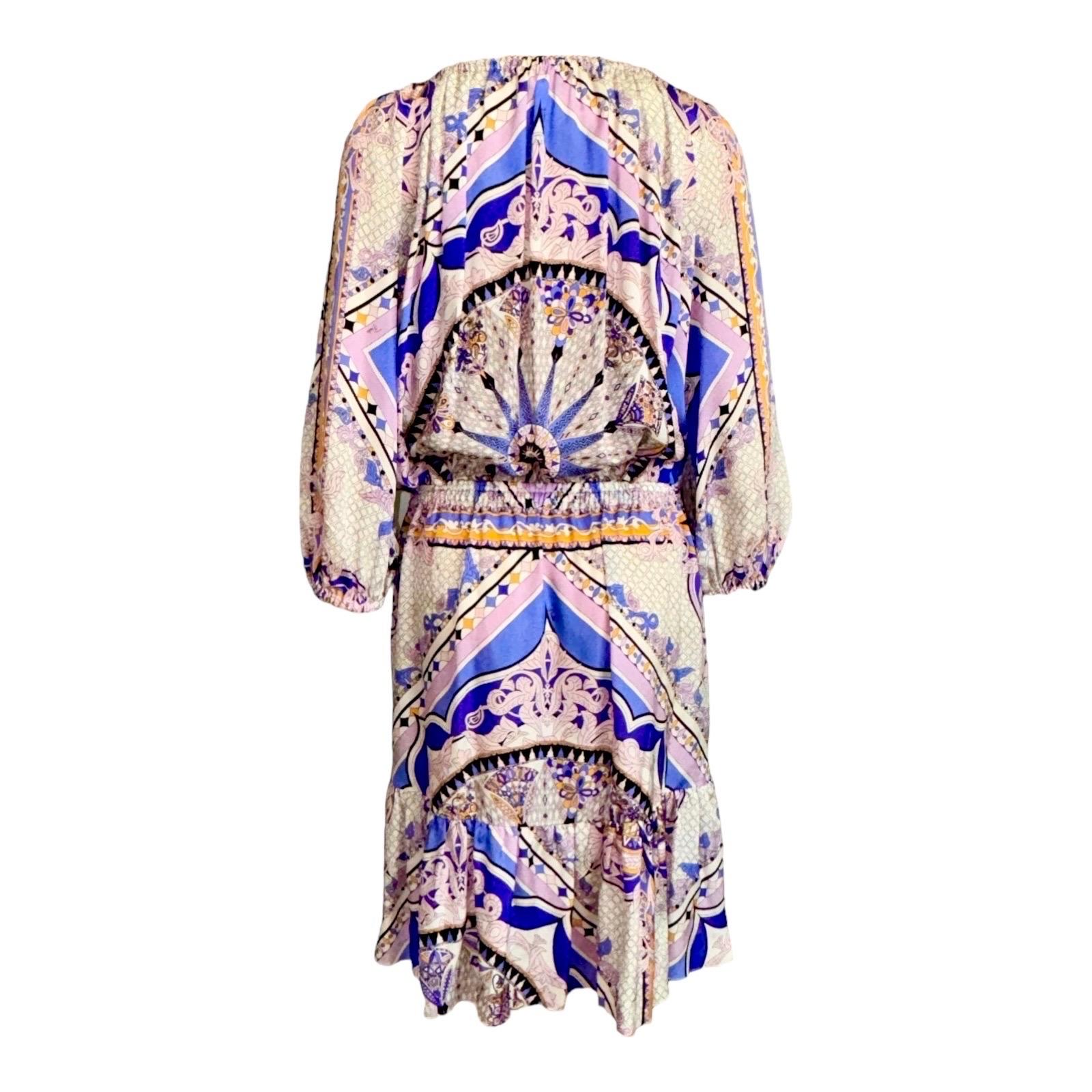 Des couleurs vives illuminent l'imprimé signature d'Emilio Pucci recouvrant une robe en soie à l'esprit libre. 
Des fronces à l'encolure, aux poignets et à la taille façonnent la silhouette vaporeuse, tandis que des houppes pendent au-dessus du trou