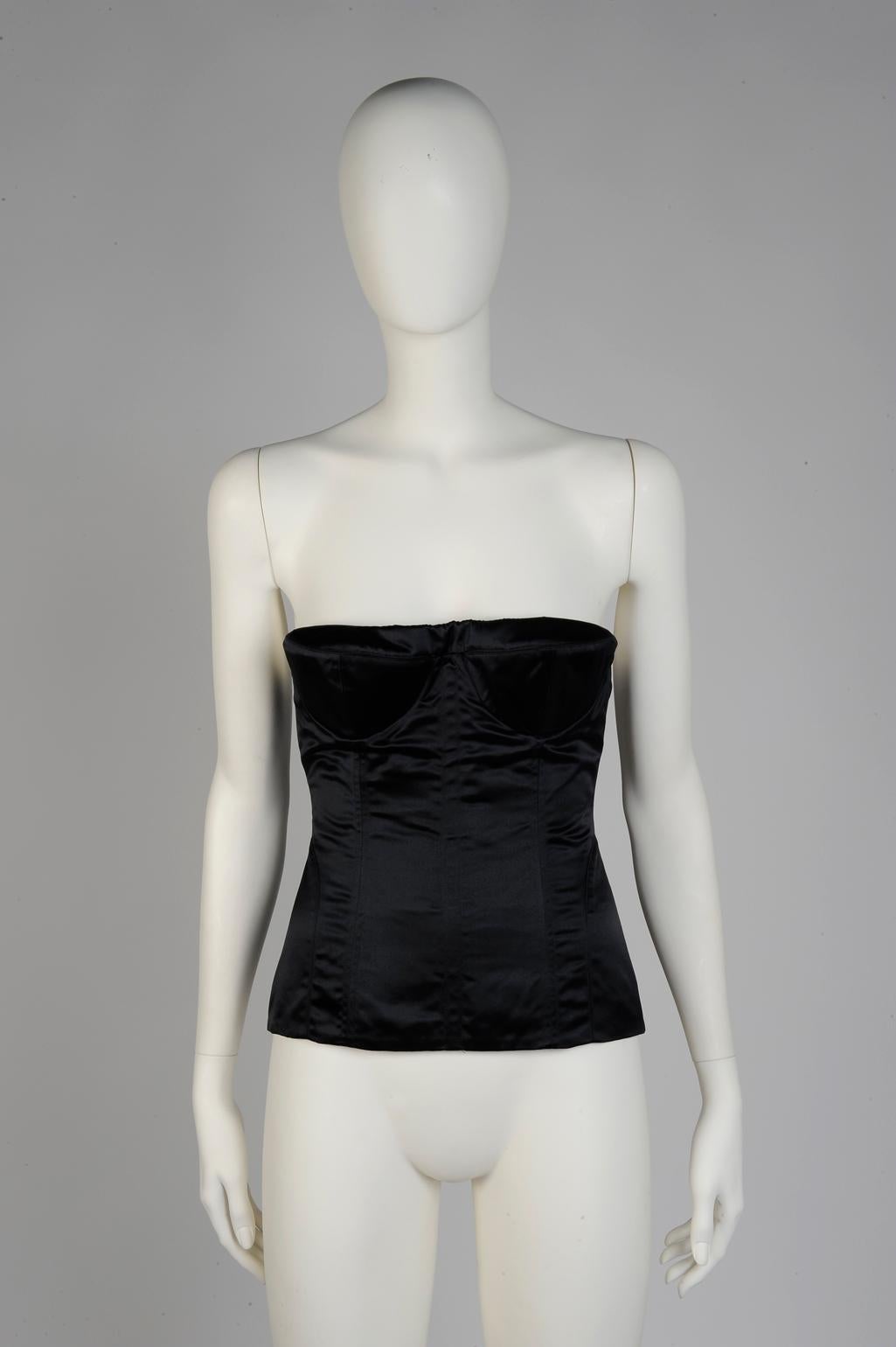 Eleva tus looks de noche con este excepcional top corsé Gucci by Tom Ford. Confeccionado en satén de seda negro brillante, está diseñado con refuerzos internos para mantener la silueta sin tirantes en su sitio. Modelado por Clara en el look 44 del