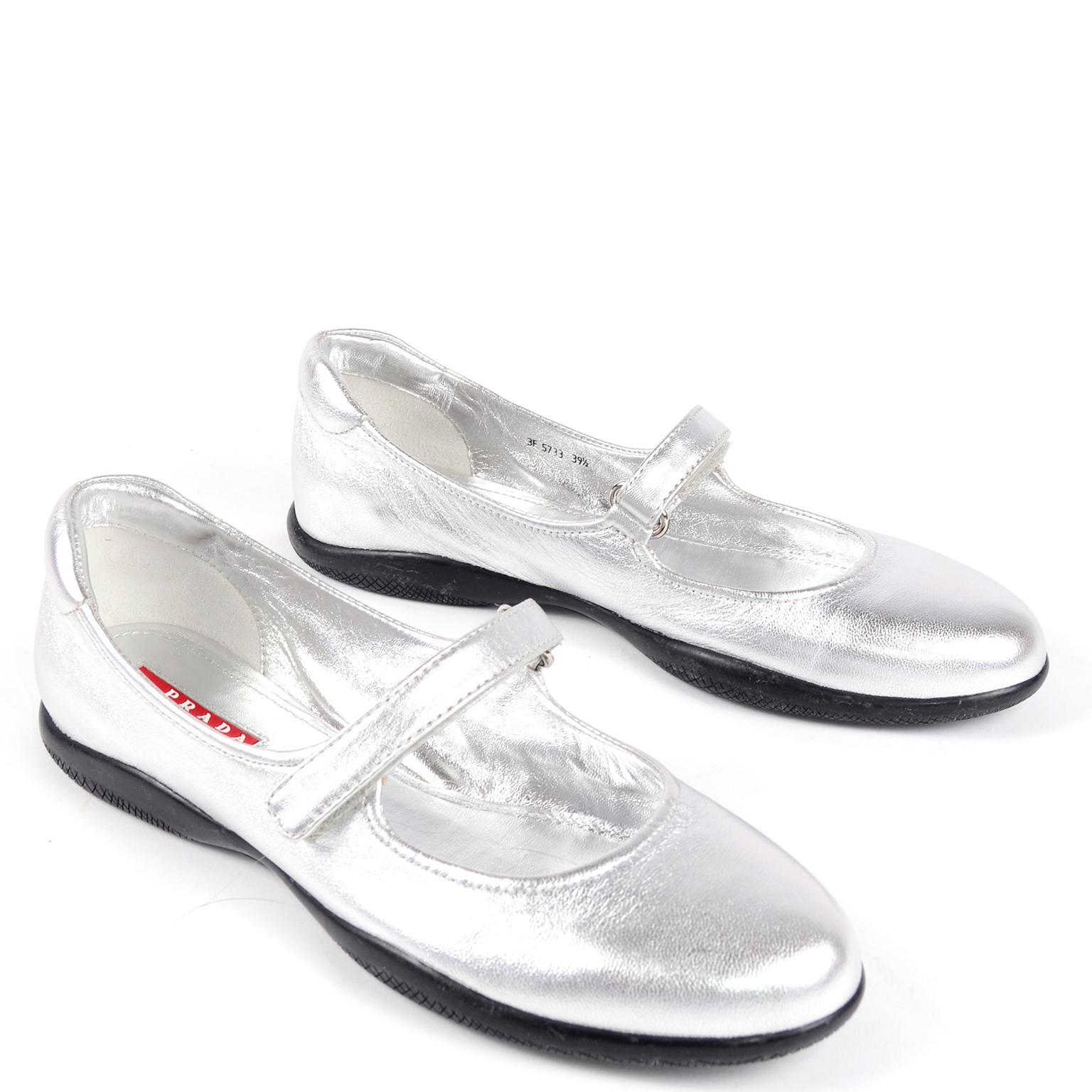 These pretty silver Prada shoes have ever been worn! These Mary Jane flats have a velcro strap, a round toe. and rubber sole. We think these can be worn casually or with holiday party dresses!  Labeled an Italian size 39.5
Measurements: 
BALL: