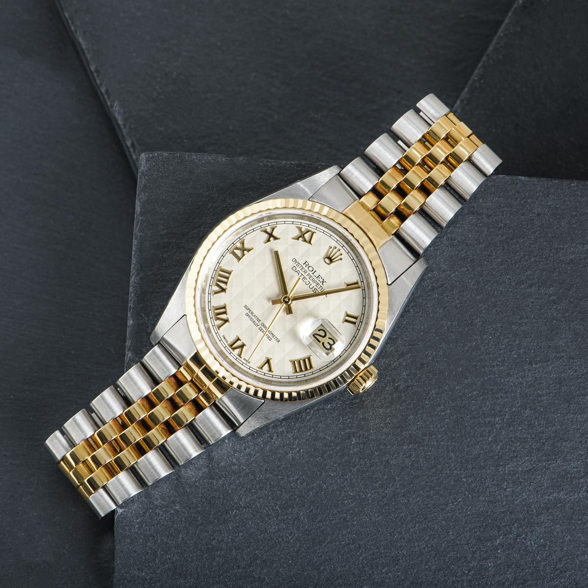 An unworn NOS 36mm Datejust by Rolex in stainless steel and yellow gold. Features a silver pyramid dial with Roman numerals and a fluted yellow gold bezel. The Jubilee bracelet comes equipped with a folding Oysterclasp. Fitted with scratch-resistant