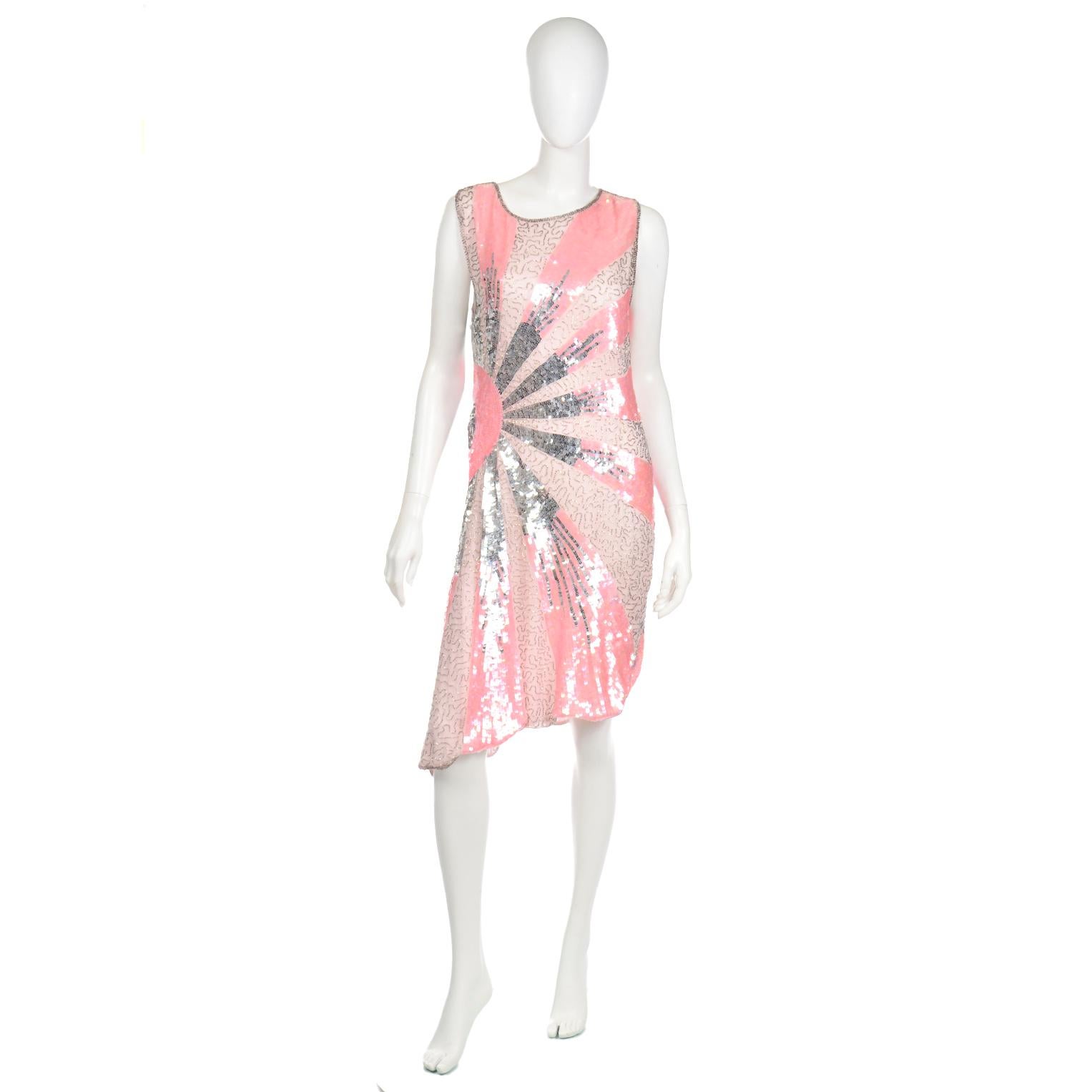 This is a stunning vintage pink flapper style evening dress with silver, pink and sequins and silver bugle beads. We love that the pattern of the beading and sequins creates a sunburst effect that radiates from the right side of the waist! The dress