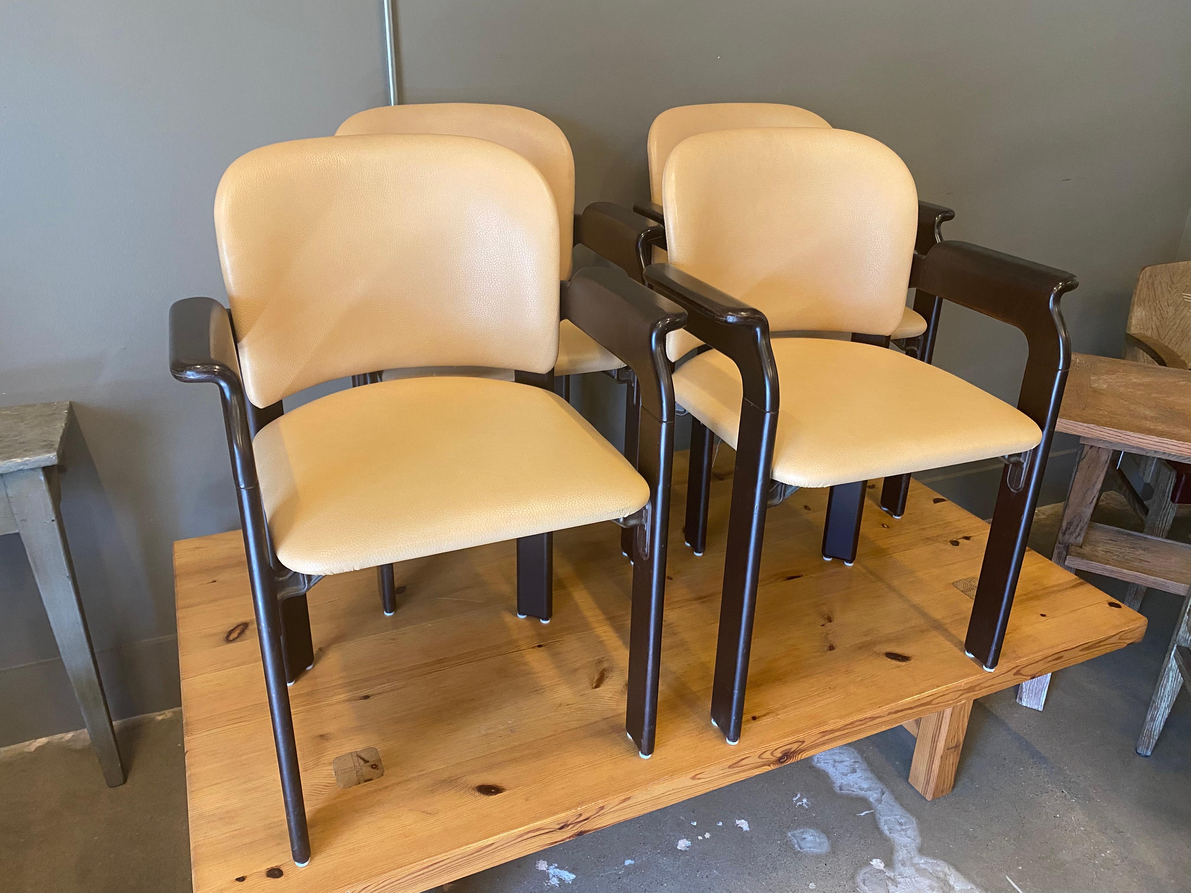 Scandinavian modern styled armed dining chairs by Robert and Trix Haussmann for Dietiker. Designed in mid-1960's with continued manufacturing. Ebonized hardwood frames and buff colored leather seats and backs. Comfortable and, because these are more