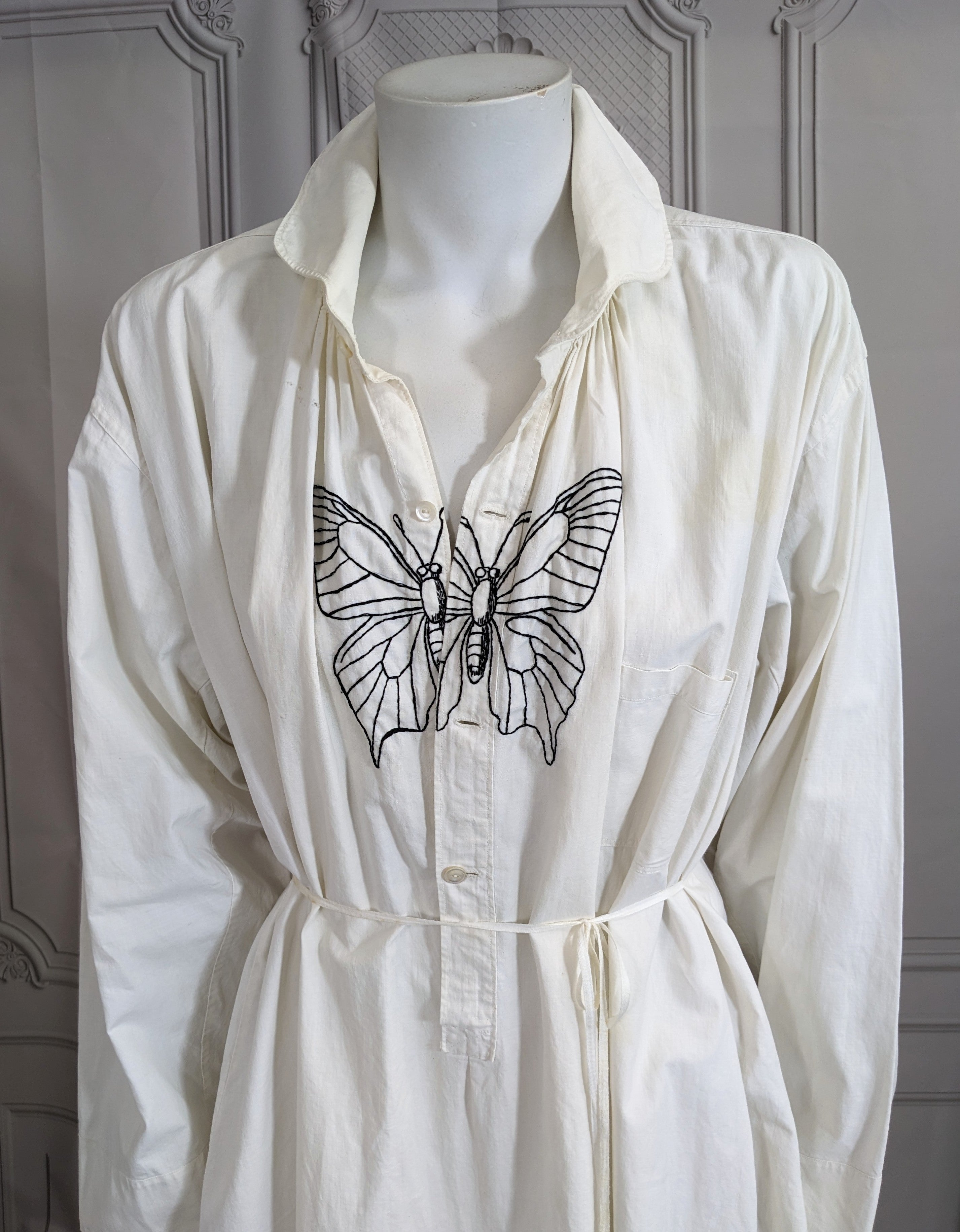 Upcyceltes, neu besticktes Baumwollkleid aus den frühen 1900er Jahren mit zeitgenössischer Stickerei von Studio VL. Handgestickt in den USA in grafischem Schwarz. Doppeltes Mirror Butterfly-Motiv auf der Knopfleiste und NY's finest Maskottchen auf