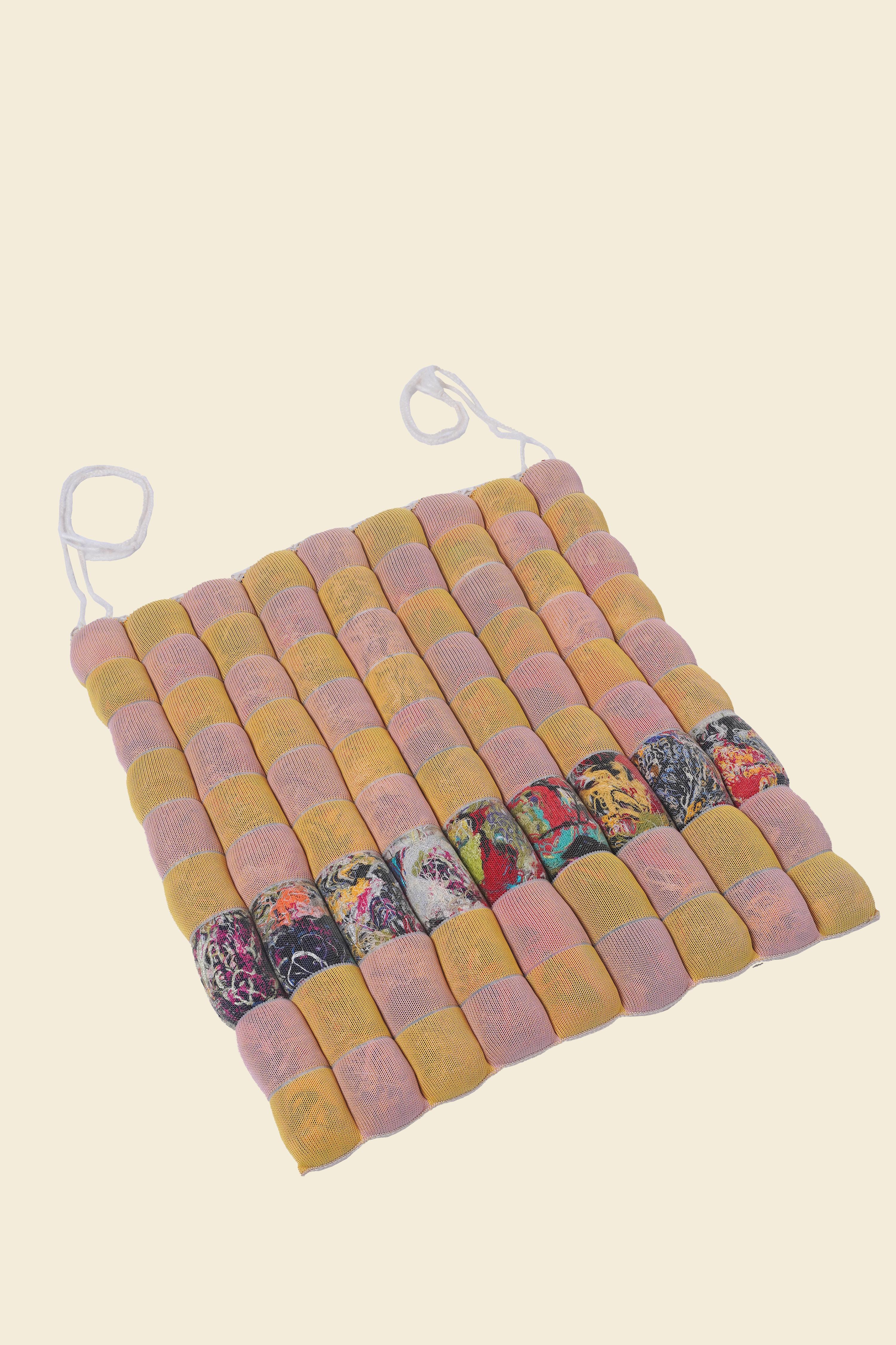 Dans l'esprit de la réutilisation et de l'upcycling, ce coussin doux et confortable utilise les déchets de matériaux comme un outil esthétique et fonctionnel. Fabriqué à partir d'un tube tricoté semi-transparent rempli de déchets de production