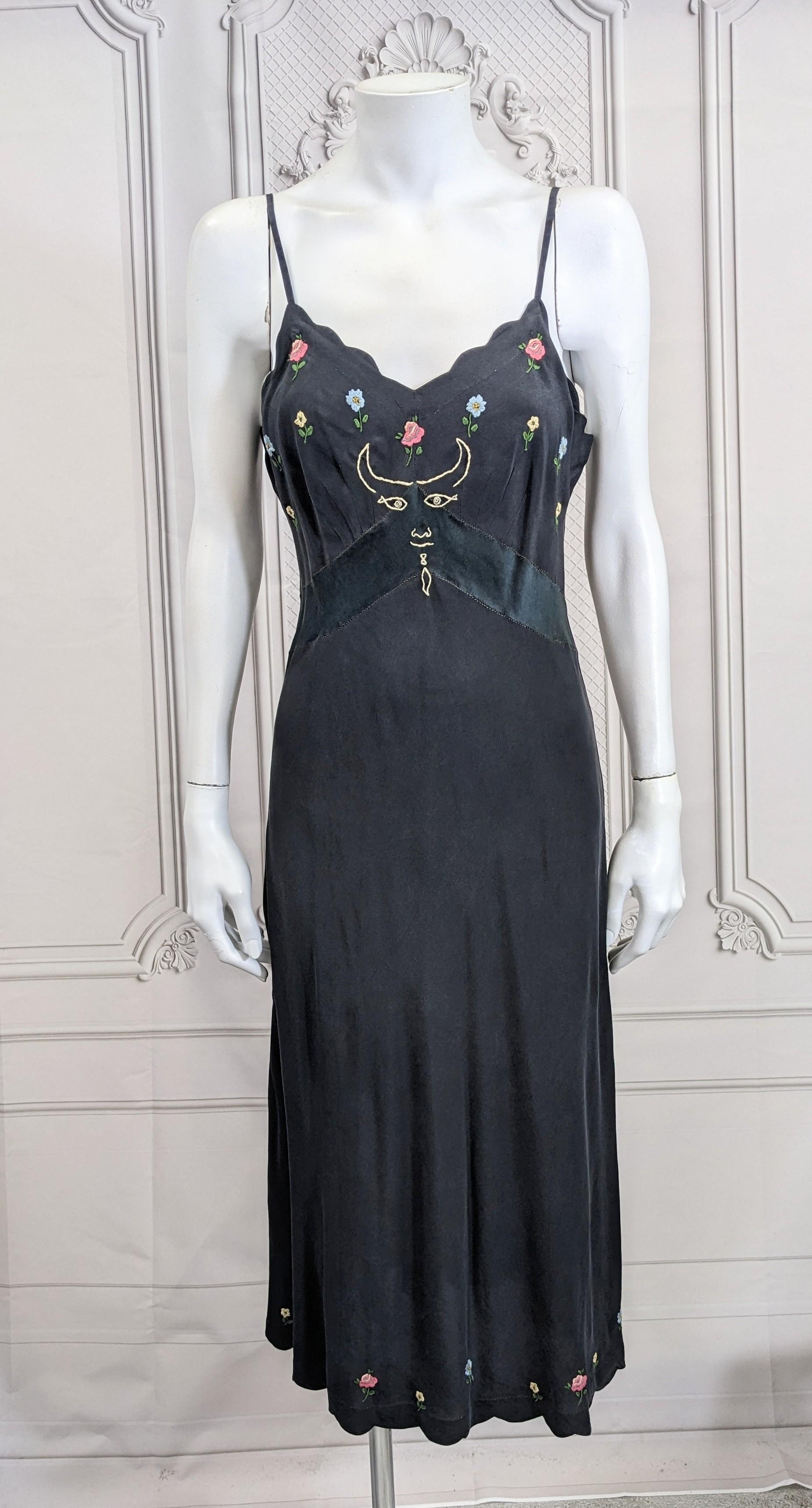 Upcycled Vintage Cocteau Slip, Studio VL. Black silk Art Deco slip with scalloped edges throughout and and embroidered florals. We have embroidered a Jean Cocteau motif across the bodice, with classic fish eyes and horns. The slip is sand washed for