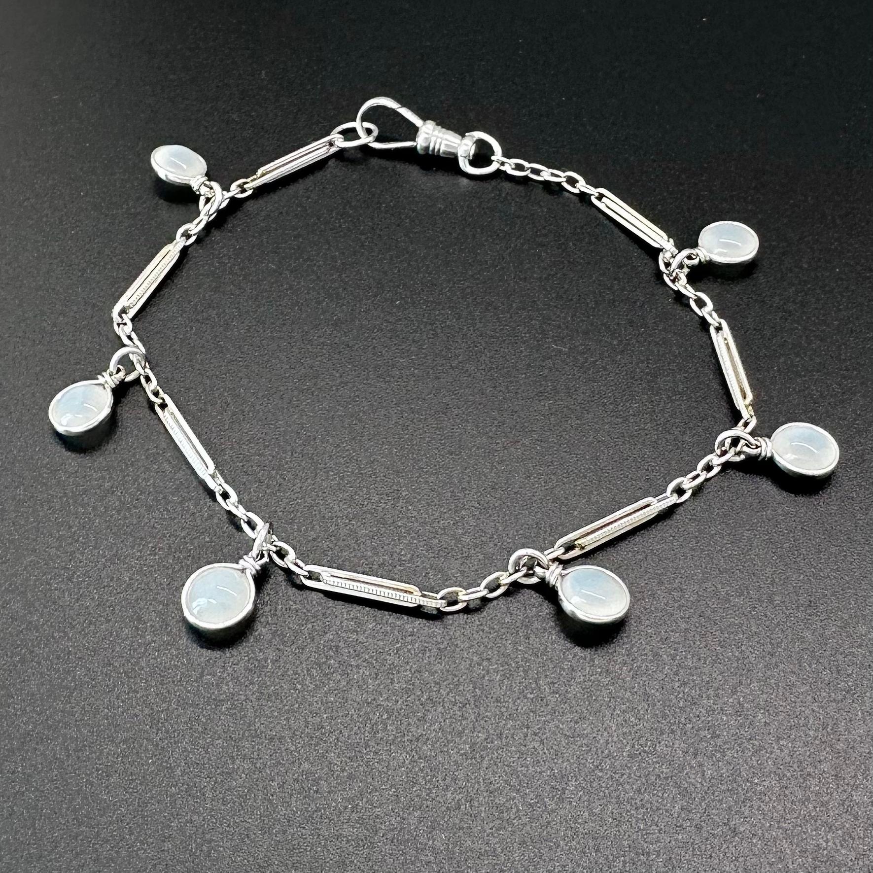 This lovely, elevated charm bracelet features an 14k white gold upcycled vintage watch fob chain paired with six lentil cut natural moonstone dangles. 

The simplicity and subtle glow of the gems highlights the beautiful antique style of the chain,